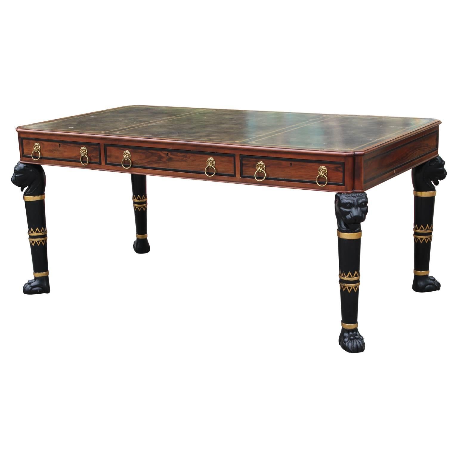 Gorgeous two-tone Brazilian rosewood executive desk by Baker Furniture featuring lovely carved lion heads at the top of each leg and brass ring lion head pulls for the three drawers. The green leather top showcases gold stamped detailing. There are