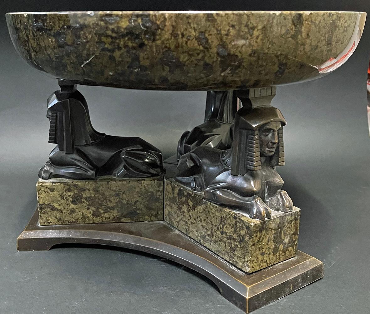 Striking and beautifully made from speckled serpentine and bronze by a French artist, this Egyptian Revival / Art Deco footed bowl or centerpiece features a wide, shallow bowl supported by three bronze sphinx figures. The stone has a rich, mottled