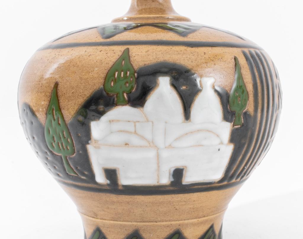 Vase en céramique de style néo-égyptien, non signé et apparemment non marqué, probablement dans les années 1940 ou plus tard. Les côtés sont ornés de motifs égyptiens et montrent d'anciens travailleurs égyptiens dans un paysage antique.

Dimensions