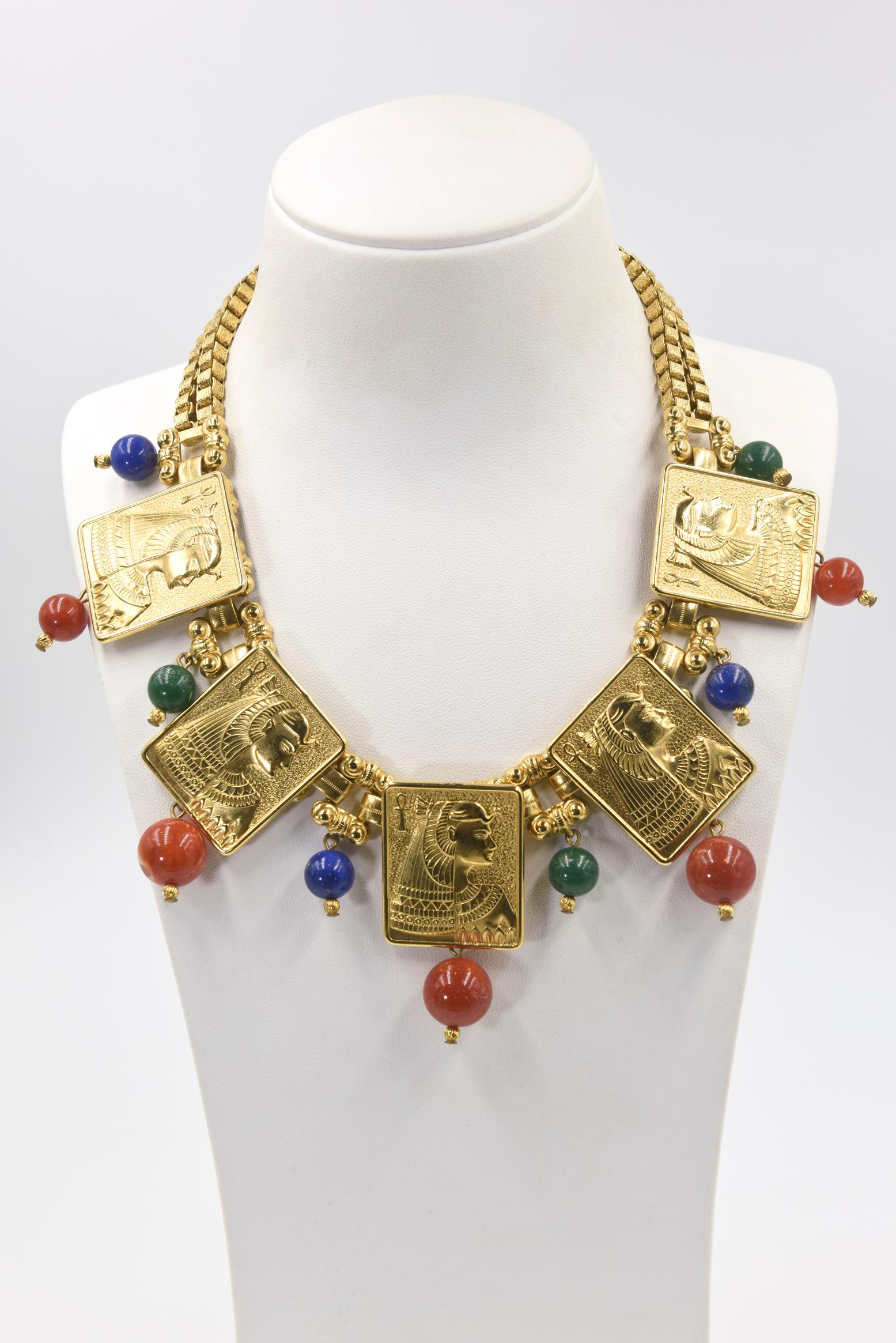 Stunning Egyptian Revival necklace featuring high relief plaques of Cleopatra accented with blue, orange and green beads.  The necklace has 5 plaques with dangling orange sunstone beads.  Between the plaques are double bridges to a rectangular link