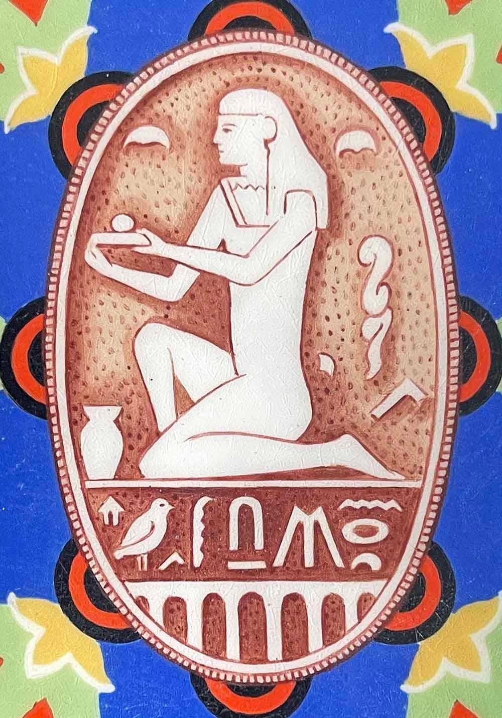 This rare -- perhaps unique -- enameled cigarette case or compact features a cartouche with a kneeling Egyptian figure surrounded by symbols and hieroglyphics on its lid, all in tones of royal blue, mint green, orange-red and spring green. The back
