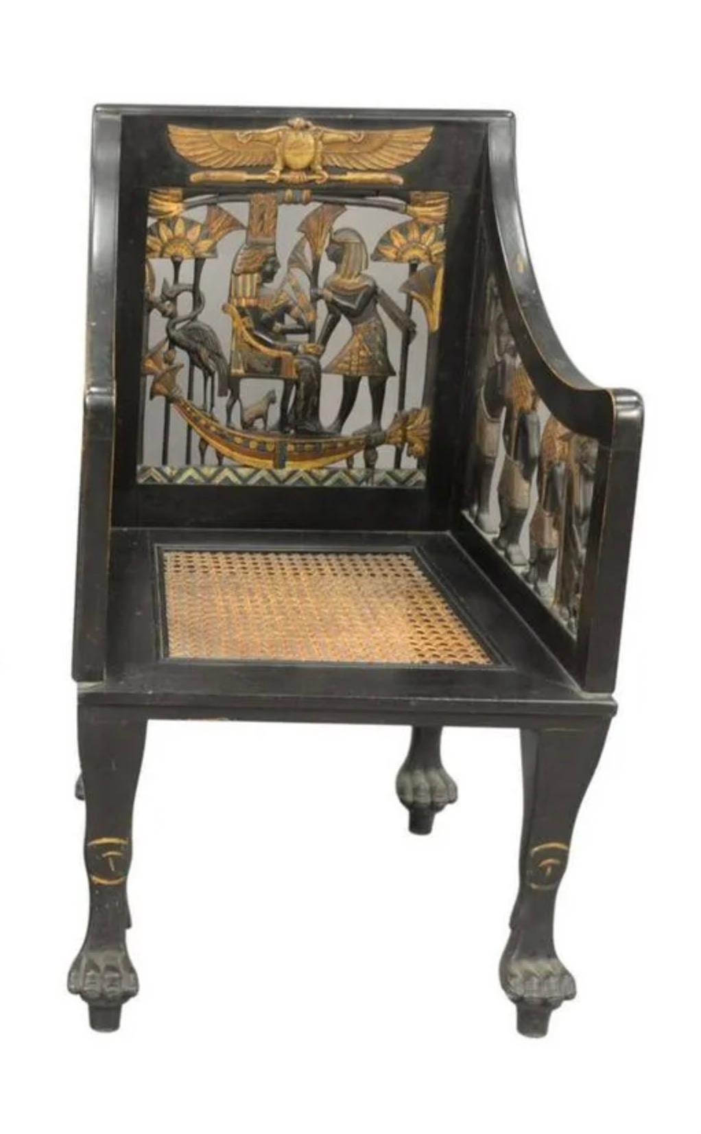 Egyptian Revival Ebonized armchair with a pierced carved back, arm support, and caned seat on paw feet.