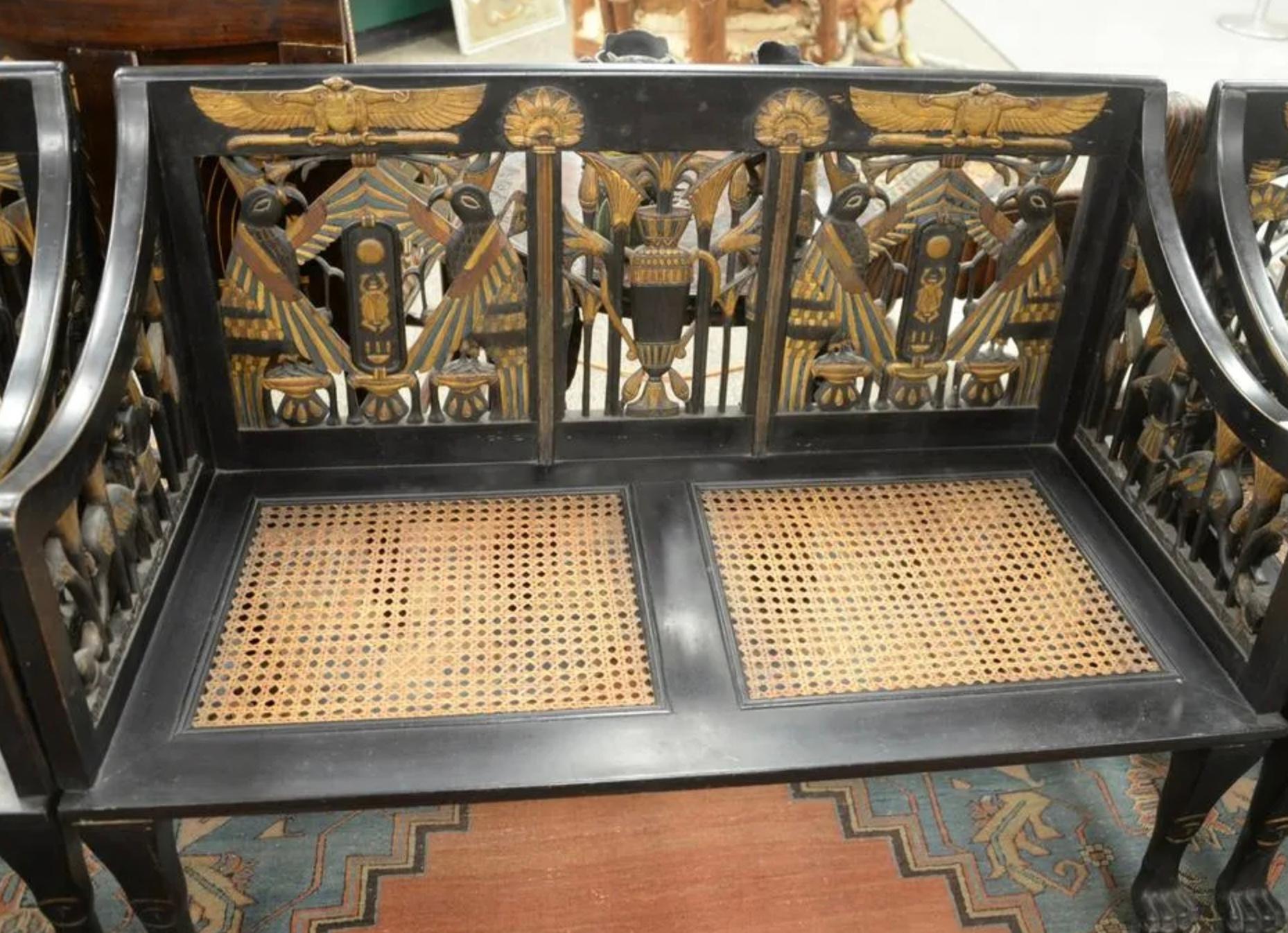 Egyptian Revival Ebonized settee, having pierced, carved back and arm supports with caned seats and paw feet