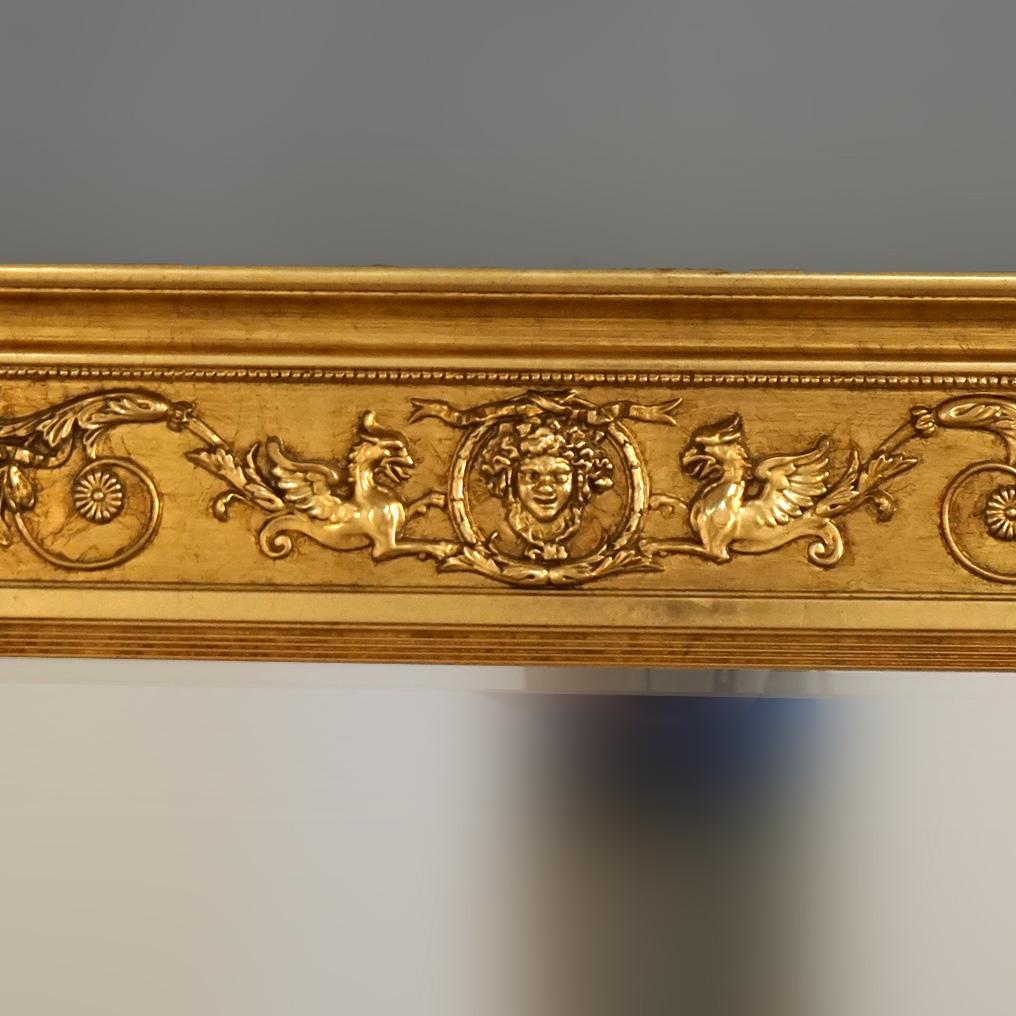 ***Ask About Reduced In-House Delivery Rates - Reliable Professional Service & Fully Insured***
Egyptian Revival Figural Triptych Three-Section Gold Giltwood Wall Mirror with Phoenix, Caryatids, Columns, Masks, Foliate Elements and Beveled Mirror