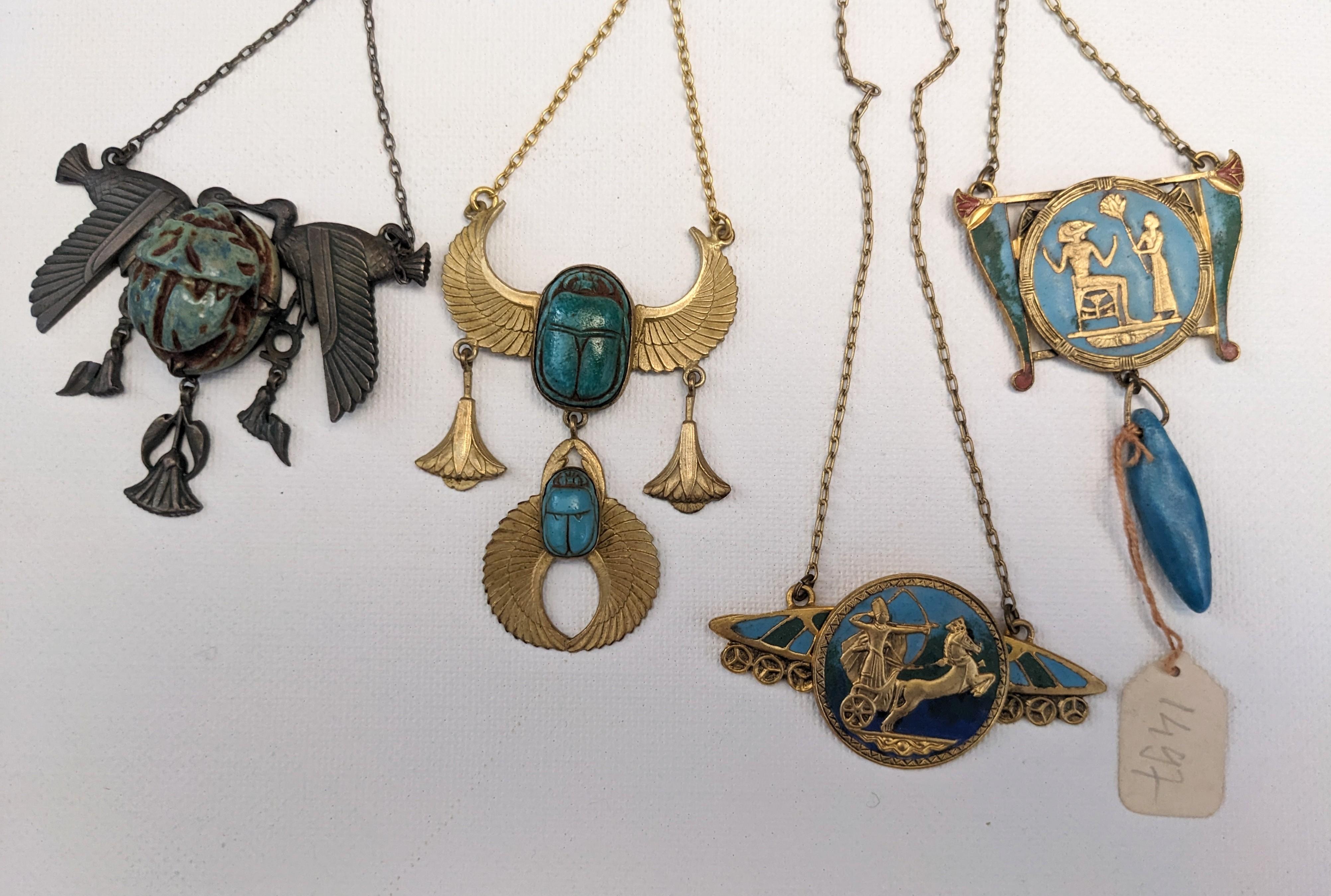 Egyptian Revival French Art Deco Necklaces from the 1920's. Old stock unworn pieces from a French factory. Many designs available in gilt or silver gilt finish decorated with enamels and glass or pottery stones. 
Various styles and designs. Some are