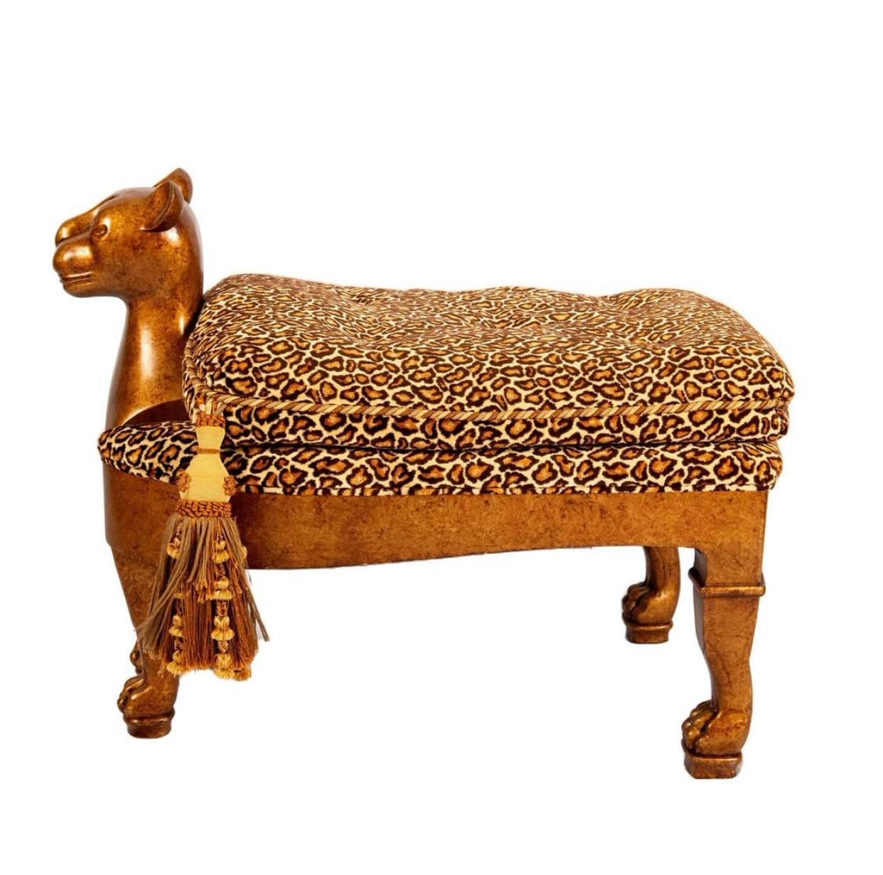 Hand carved and gold leaf finished whimsical wooden bench carved as a majestic cat. The seat is covered in a plush leopard print button tufted upholstery, adorned with a pair of beautiful large Tassels to either side of the neck. 
Dimensions: 38