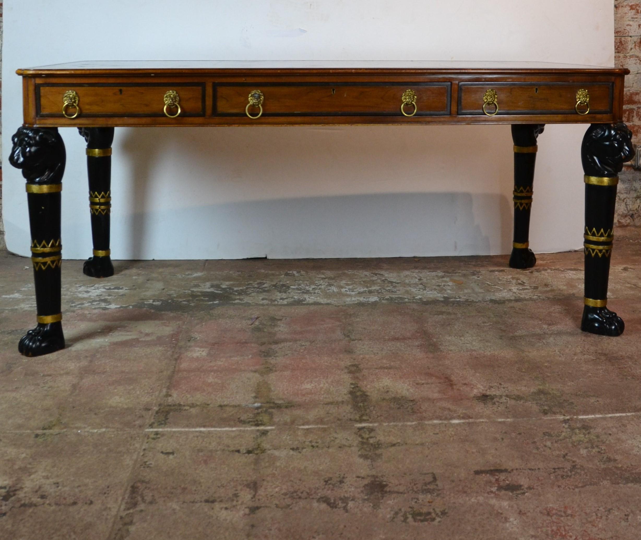 Gorgeous two-tone Brazilian rosewood executive desk by Baker Furniture featuring lovely carved lion heads at the top of each leg and brass ring lion head pulls for the three drawers. The brown leather top showcases gold stamped detailing. There are