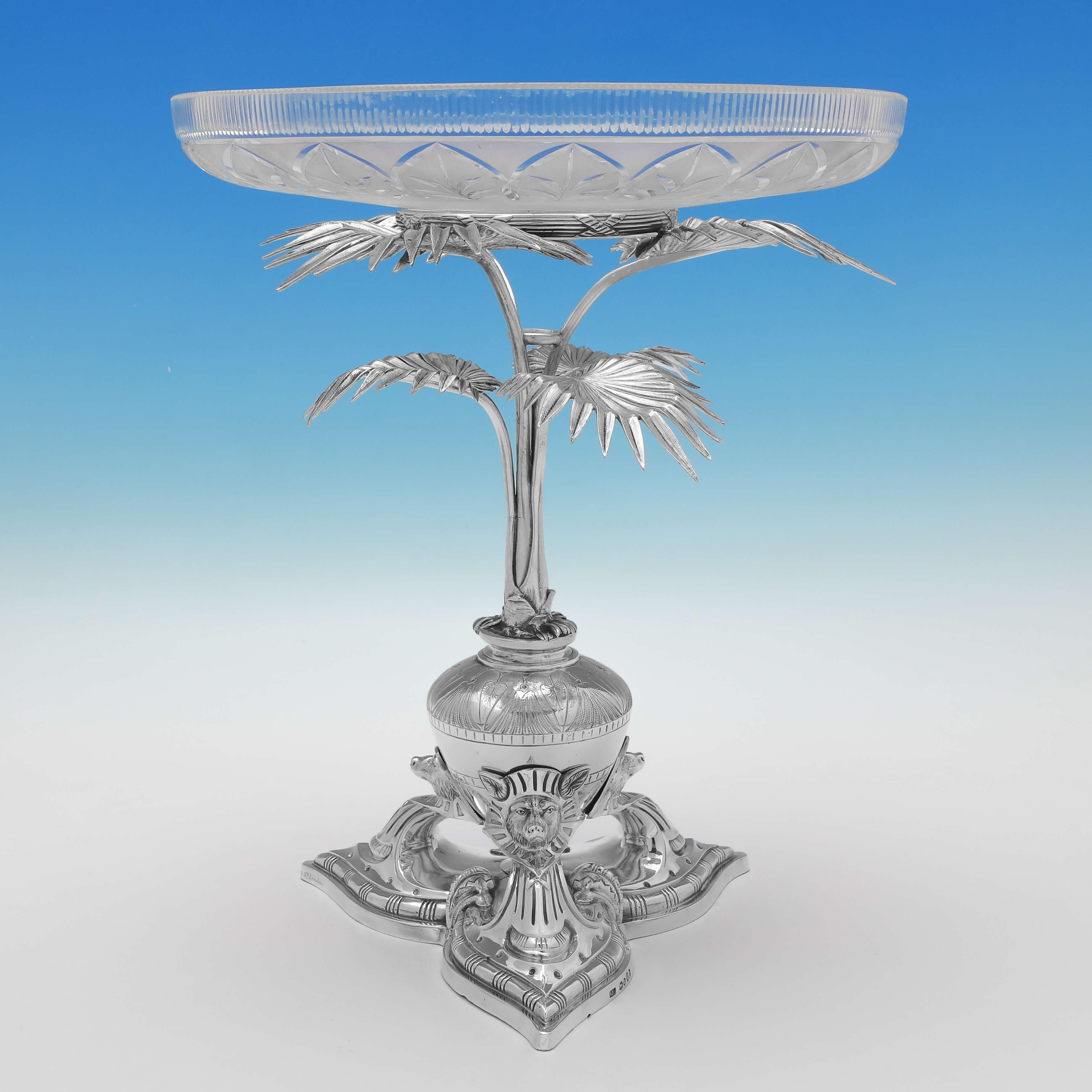 Hallmarked in London in 1871 & 1874 by Alexander Macrae, this striking pair of Antique Sterling Silver Compotes (or Dessert Stands), are in the Egyptian Revival style, featuring Anubis masks to each foot, and palm tree supports to the glass dishes.