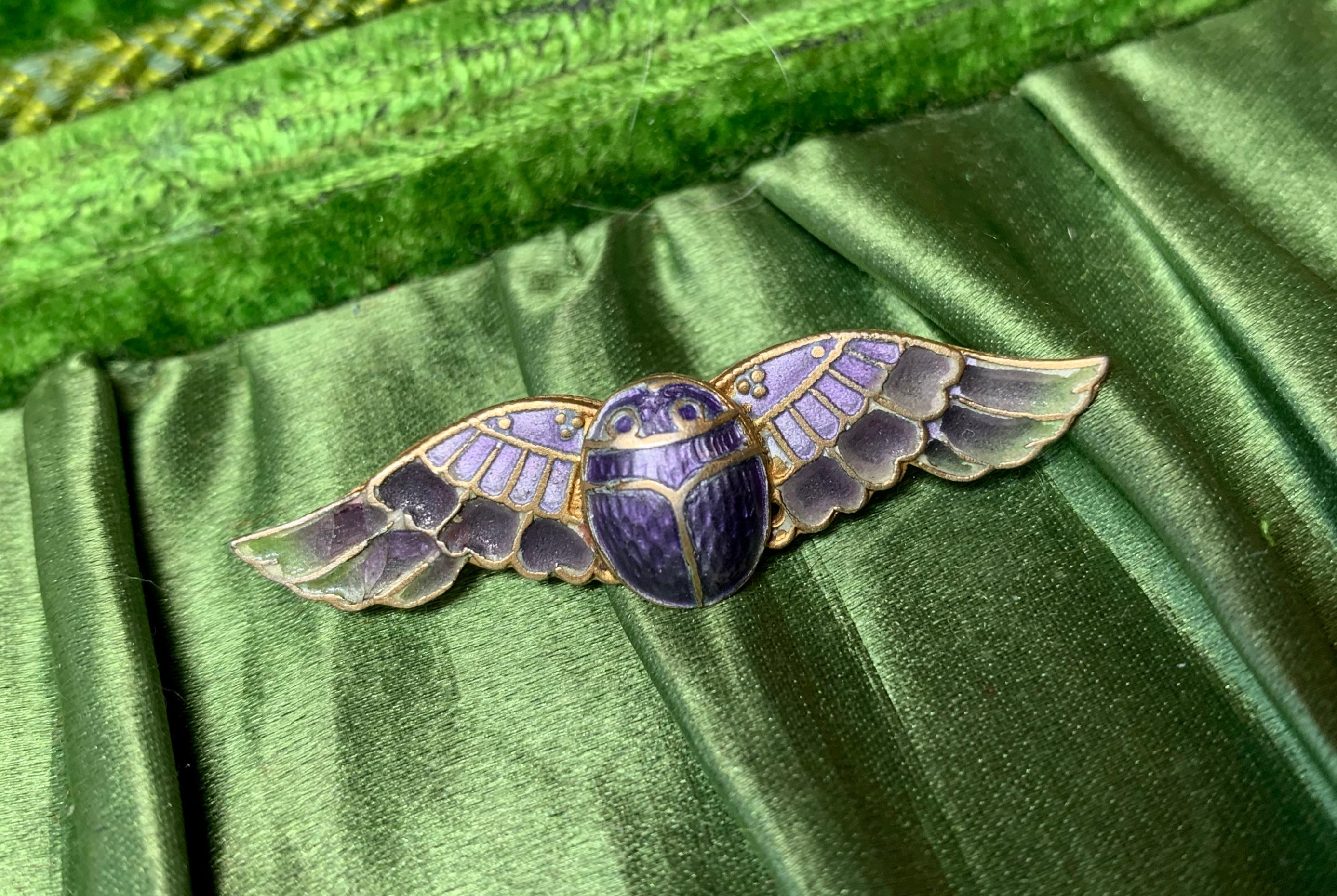 A rare Art Deco Egyptian Revival masterpiece of a Winged Scarab Insect Brooch done in Plique a Jour Enamel over Silver.  The Museum Quality brooch depicts a winged Scarab beetle, one of the signature motifs of the Egyptian Revival movement. 
The