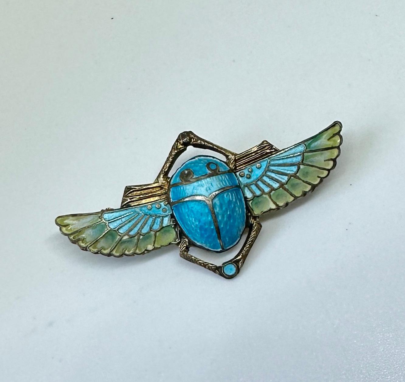 Indulge in a rare Art Deco Egyptian Revival masterpiece of a Winged Scarab Insect Brooch done in Plique a Jour Enamel over Silver.  The Museum Quality brooch depicts a winged Scarab beetle, one of the signature motifs of the Egyptian Revival