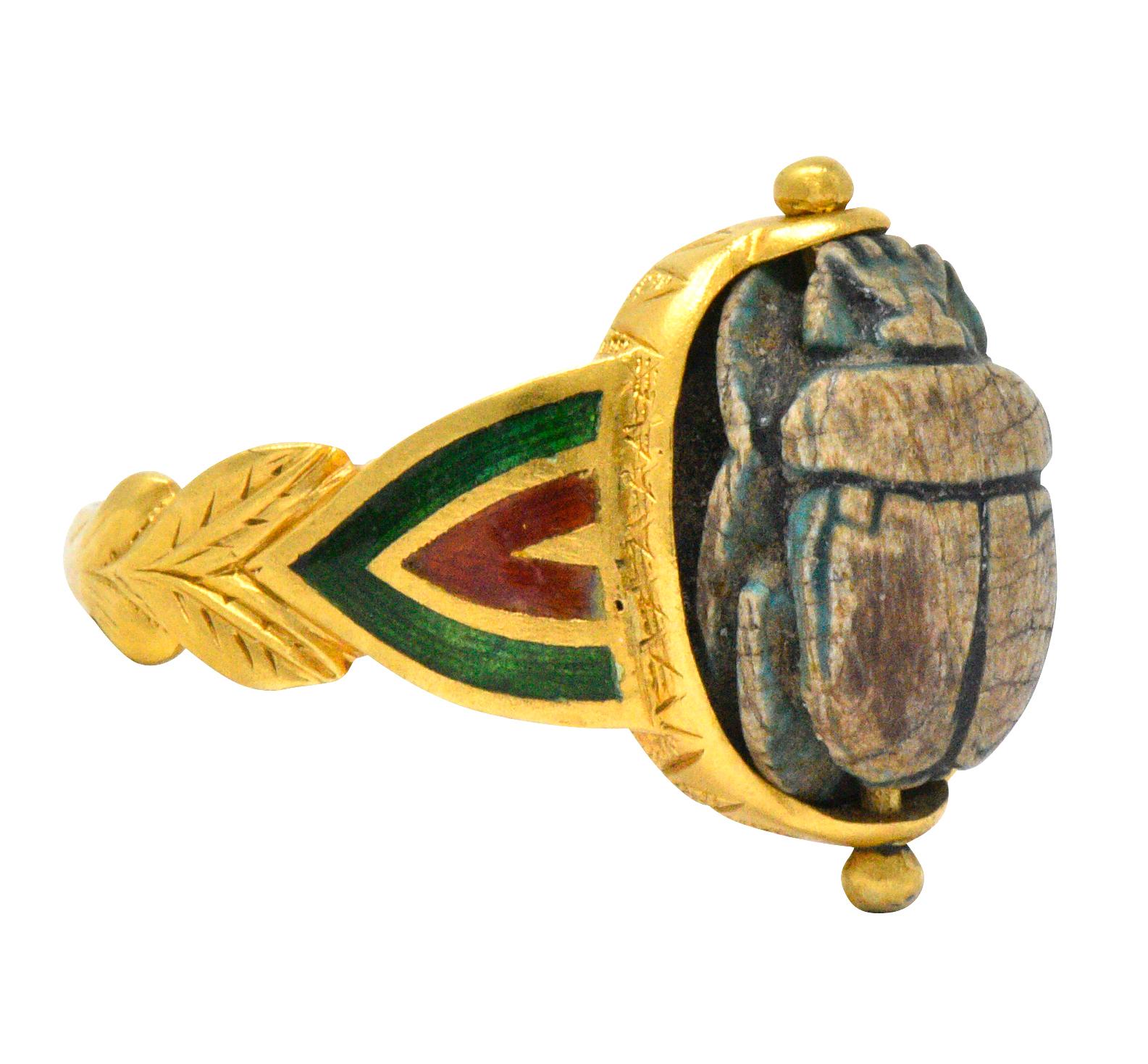 Centering scarab with minor remnants of faience

Green and red enamel chevron detail on shoulders

Matte gold finish with leaf detail

Tested as 14 karat gold

Ring Size: 9 1/2 & Not Sizable

Top Measures: 17 x 10 mm and sits 7 mm high

Total