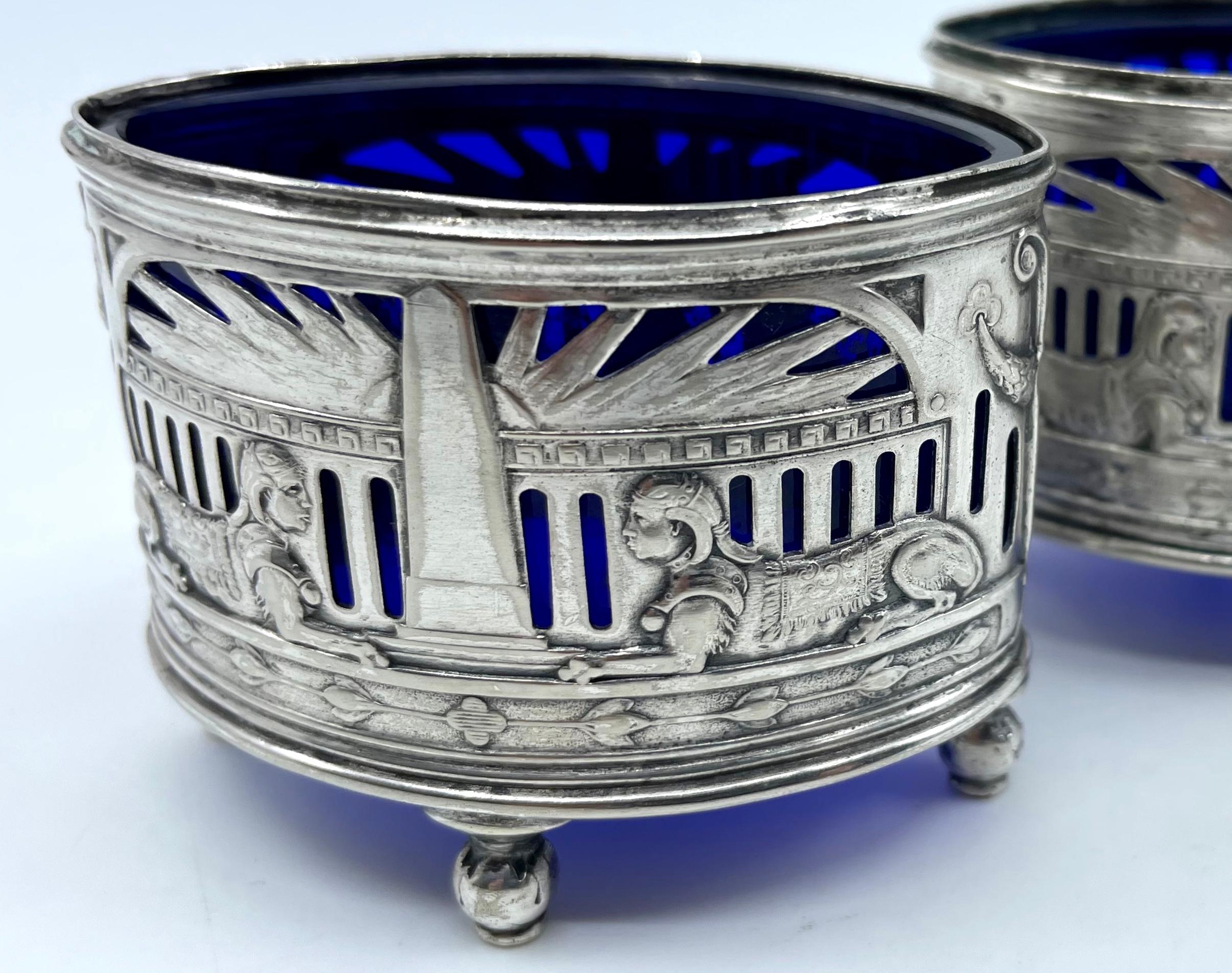 Egyptian Revival silver salt cellars. Pair English sterling silver Egyptian Revival salt cellars with repoussè with original cobalt ovoid shape liners with sphinxes, obelisks, sunburst and other neoclassical decorations. Fine pair of silver salts