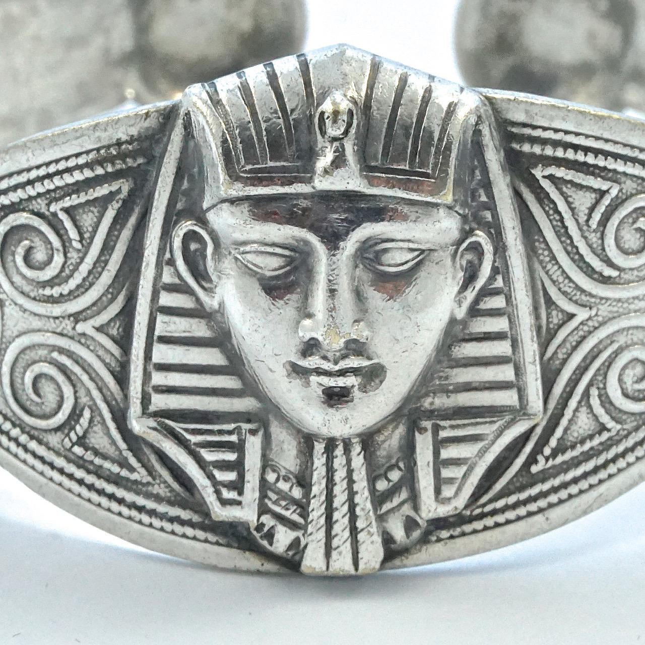 Wonderful Egyptian Revival silver bangle, featuring a centre pharaoh flanked by two elephants, with ornate decoration to the band. Tested for silver. It is probably of North African origin, as it has a stamp with the Algerian star and crescent moon.