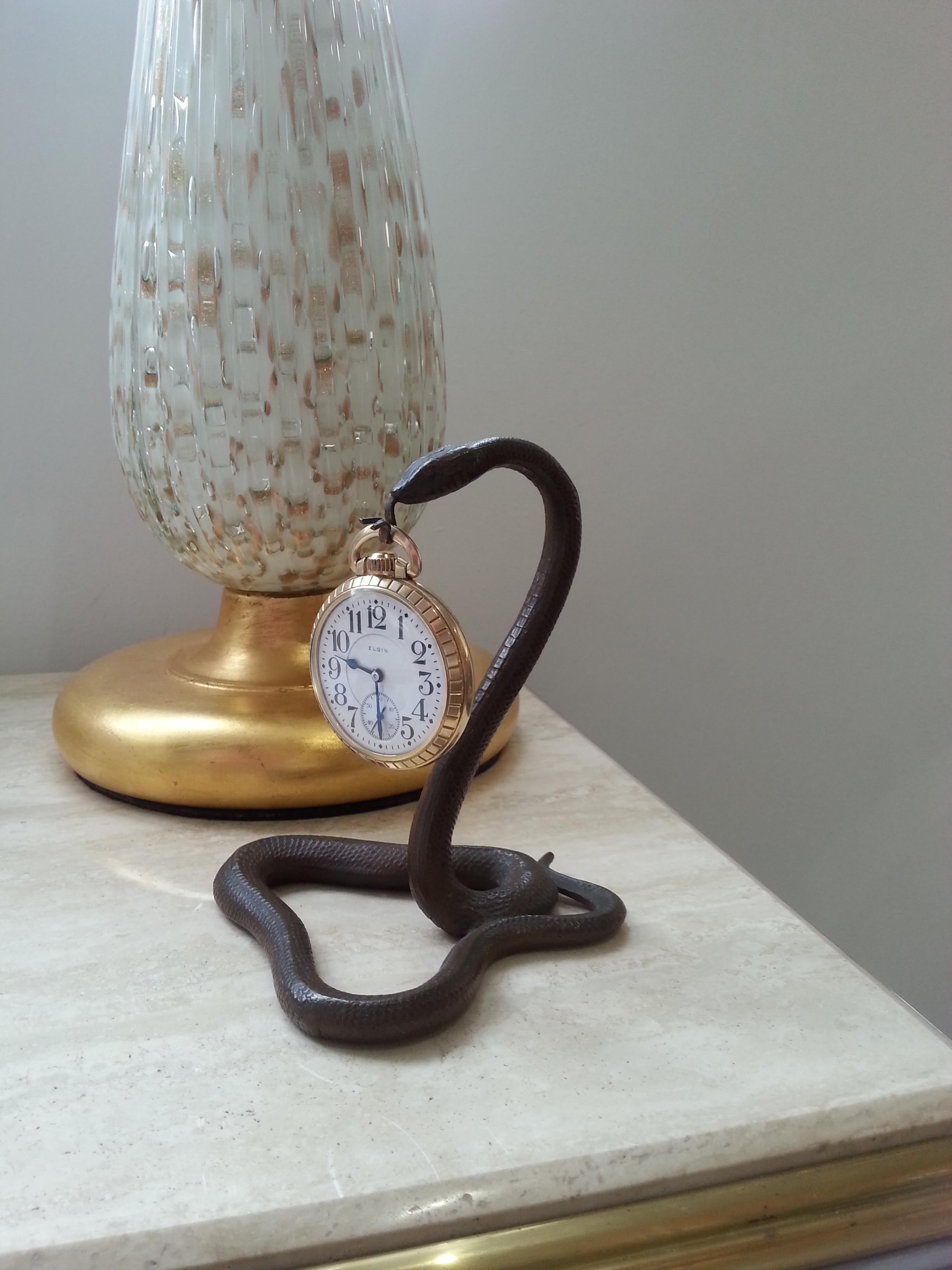 Este elegante porta-relojes del renacimiento egipcio francés data de principios del siglo XX y está fabricado en bronce fundido. El reloj de bolsillo Elgin se incluye con el soporte.

Nota: Las dimensiones de la serpiente son 5,13
