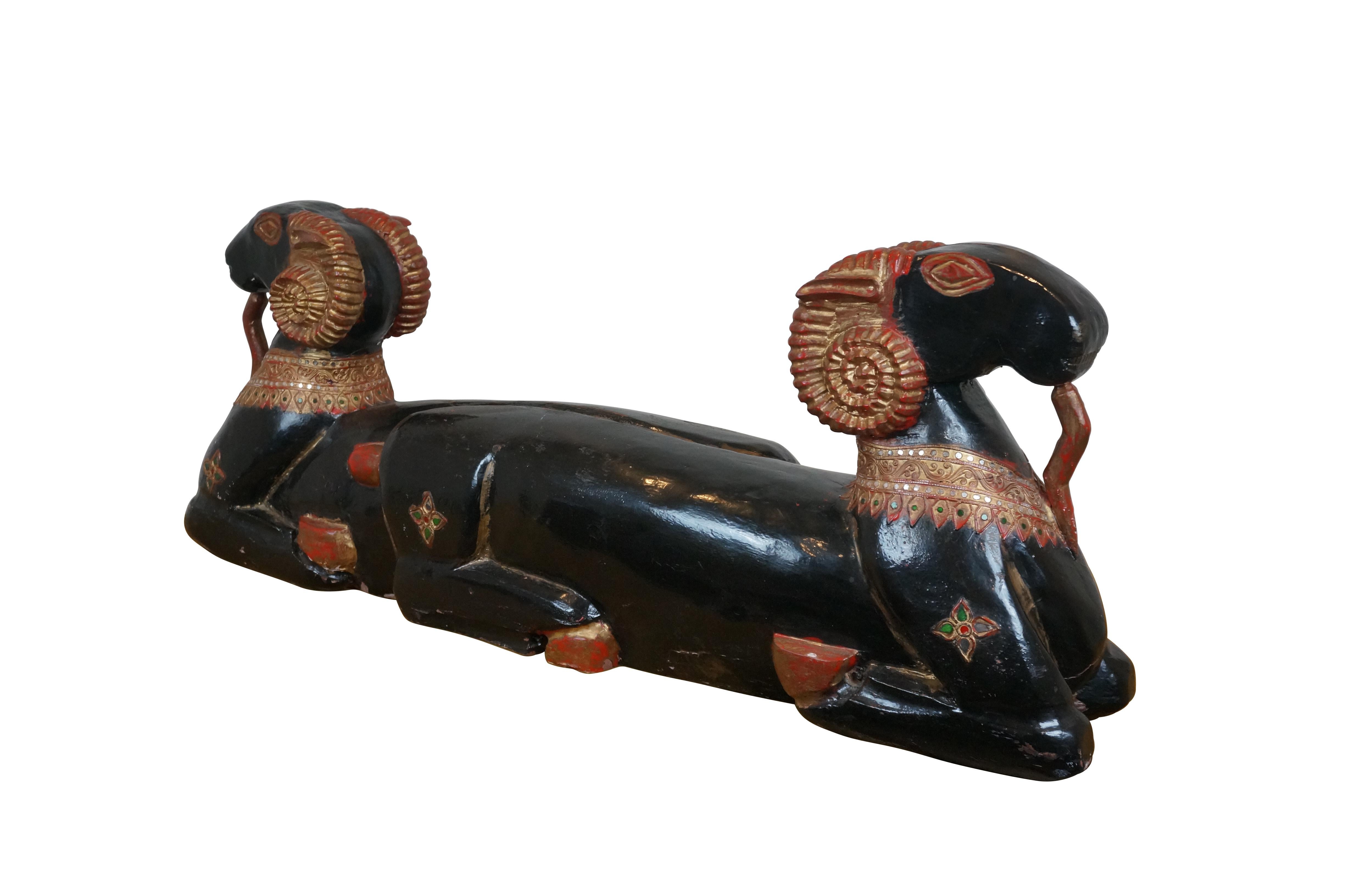 Vintage Egyptian Revival carved wood sculpture depicting a pair of reclining goats / rams facing opposite directions, decorated with intricate necklaces and beards, finished in black lacquer with red and gold details.

Dimensions:
41