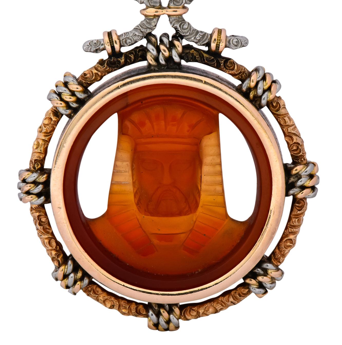 Centering a deeply carved carnelian depicting the image of a young Pharaoh in headdress with reverse side depicting the same Pharaoh, older, with a majestic beard

Set in a high polished gold surround with an ornately engraved gold frame with