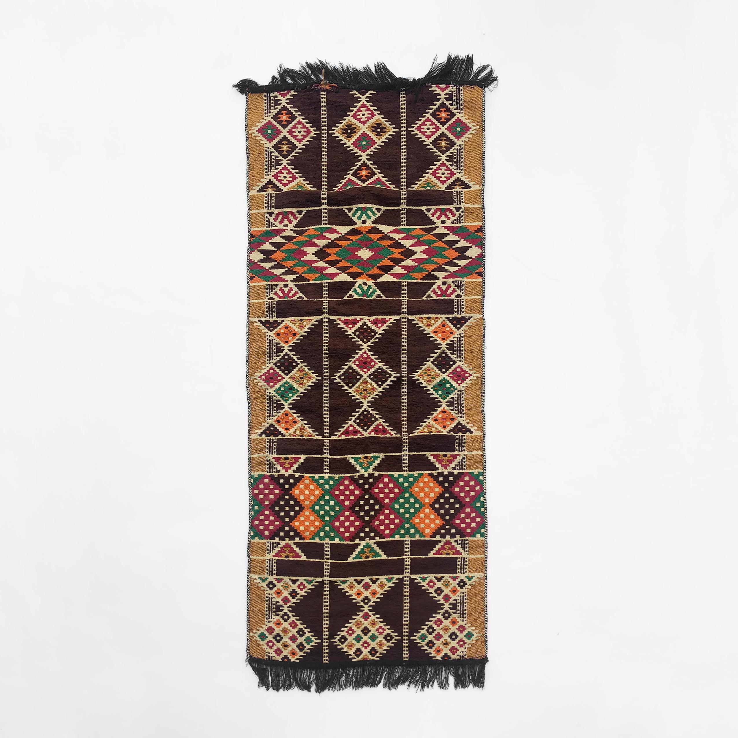 This vintage 1990s cotton mix rug, imported from Egypt, is patterned in an exciting geometric way, with a mix of browns, reds, greens, and yellows. The edges of the rug are fringed, and the runner material soft and comforting to the touch. 

These