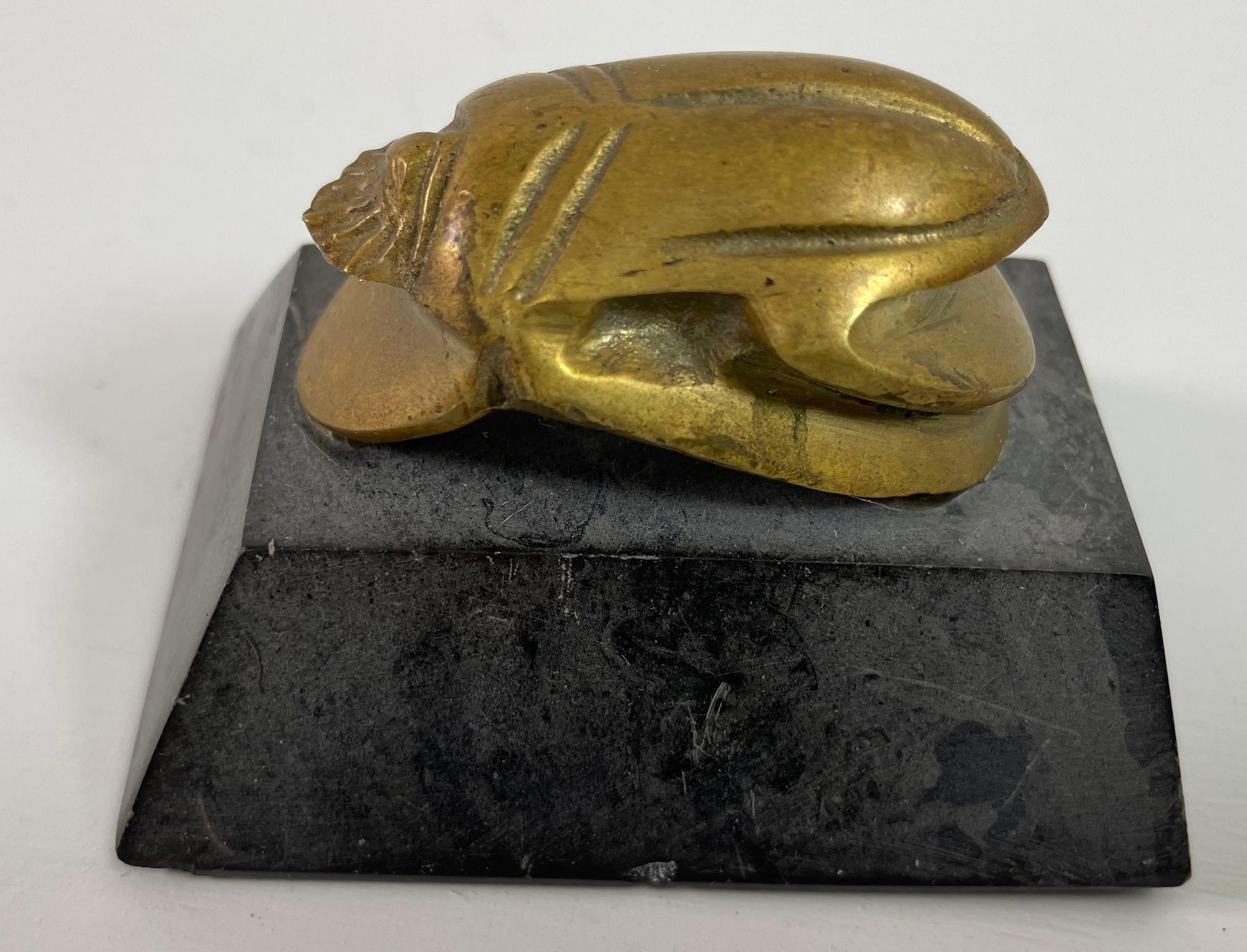 Egyptian Scarab Brass Beetle Figurine on stone stand after the Egyptian Museum antiquities.A unique and beautiful addition to any Egyptian Art Deco collection.
This Vintage solid cast brass Egyptian scarab beetle sculpture figurine on a black stone