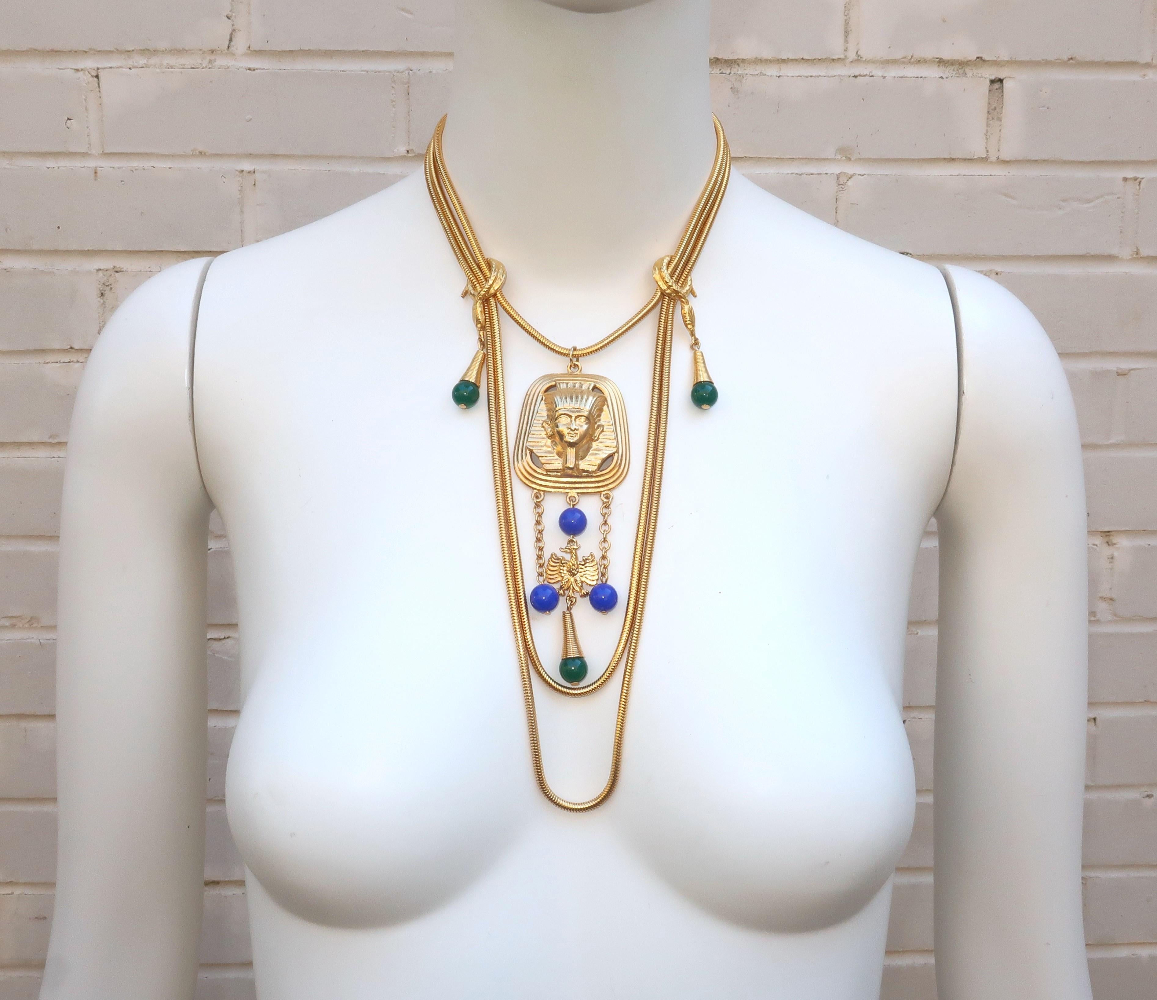 1970's Egyptian style multi strand necklace in a gold plated metal with blue and green resin beads.  The three strand necklace is designed with graduated lengths of serpentine chain accented by snake stays and a Pharaoh pendant.  Outfitted with a