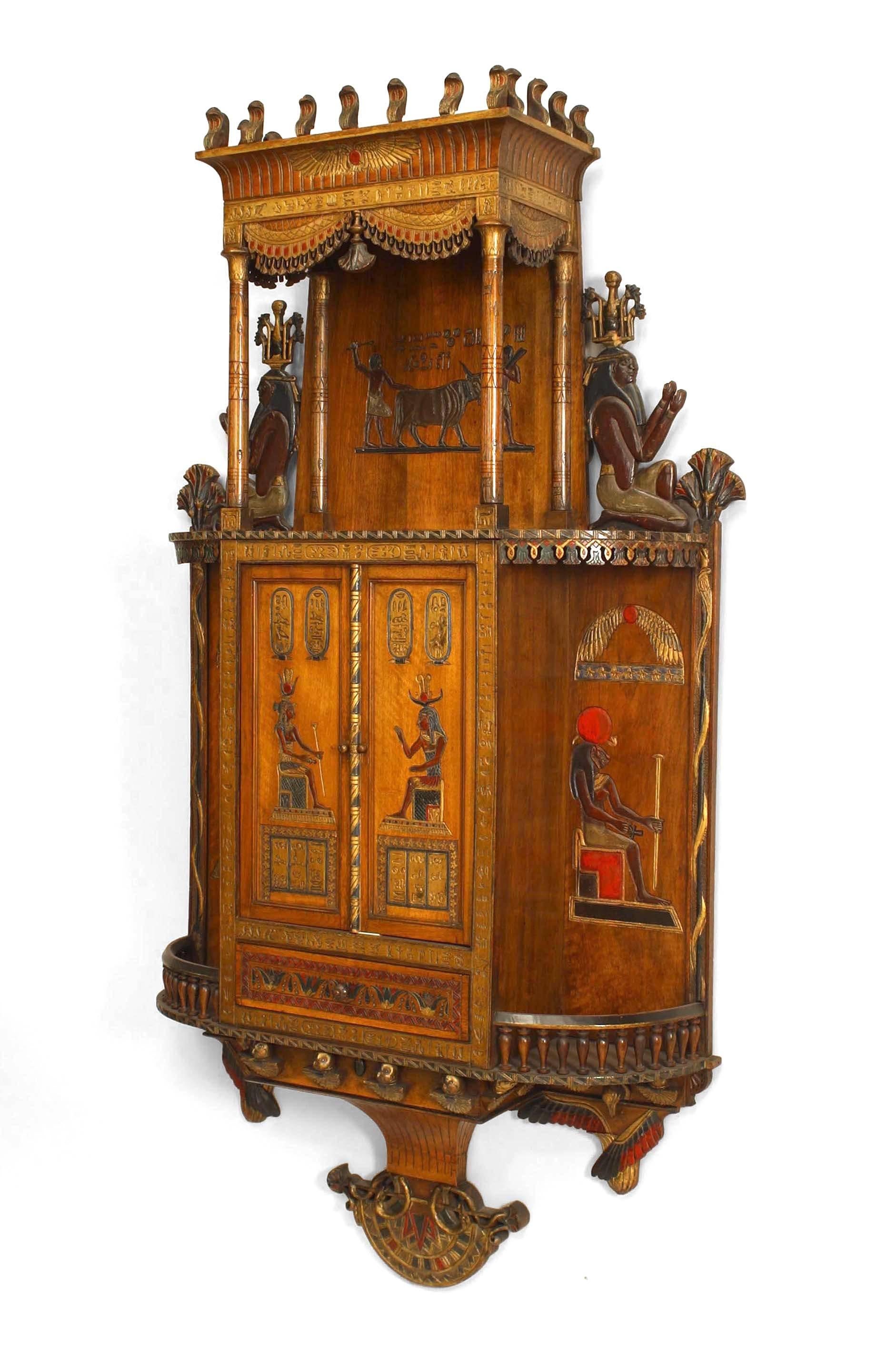 Egyptian-style (19/20th Century) painted hanging wall cabinet with carved & decorated figures and 2 front doors above a single drawer with 2 side shelves
