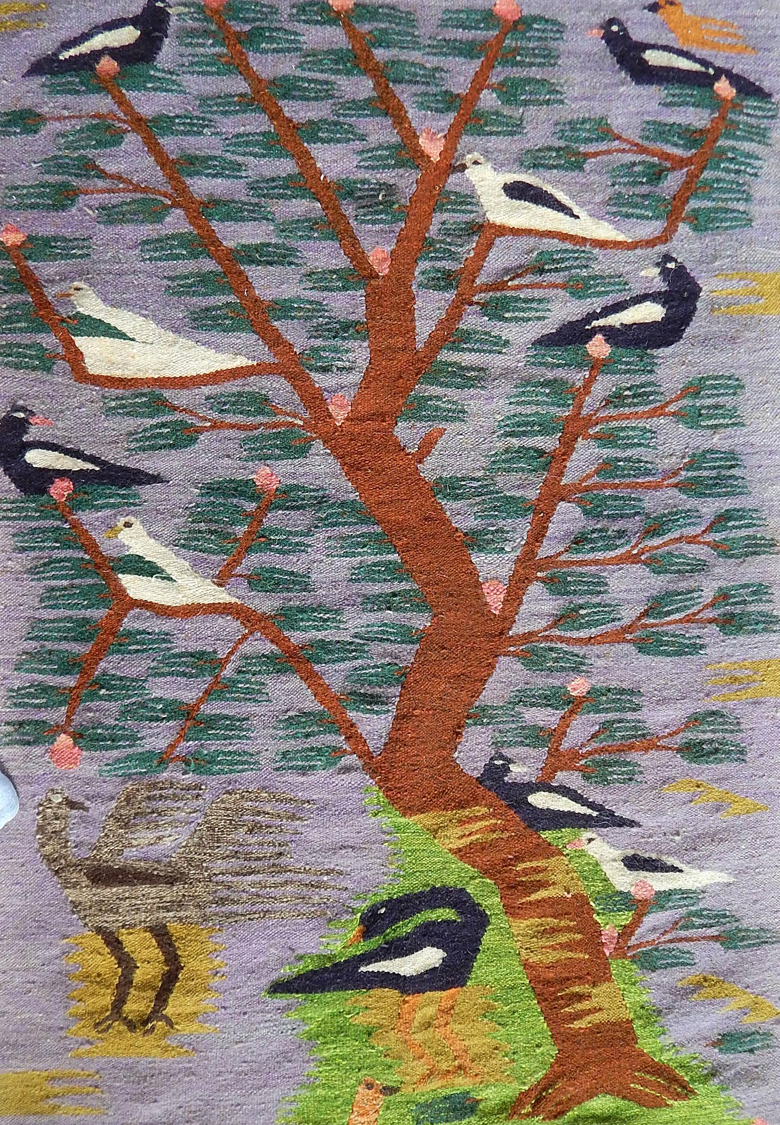 This remarkable weaving, using yarns in shades of pale purple, burnt umber, ruddy brown and deep blue, is a masterpiece of post-war Egyptian artisanry. It depicts a crowd of birds in and around a stylized tree and was influenced by the work of the