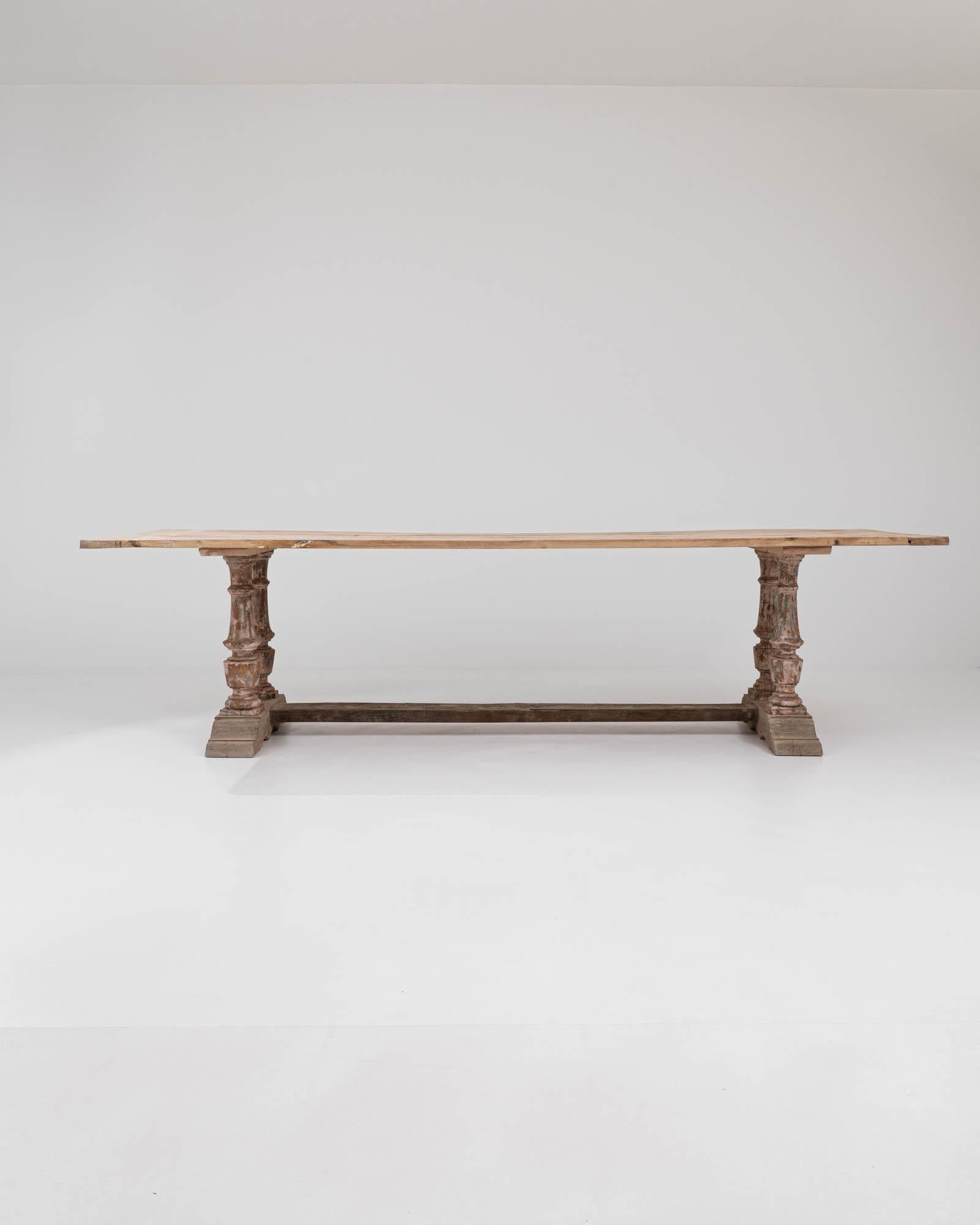Dieser in Nordafrika hergestellte Esstisch vereint eklektische Elemente in seinem einzigartigen Design. Die Tischplatte aus rohem Holz ruht auf einem gealterten Sockel mit vier kunstvoll geschnitzten Balustern, die an stabilen Klammerfüßen befestigt