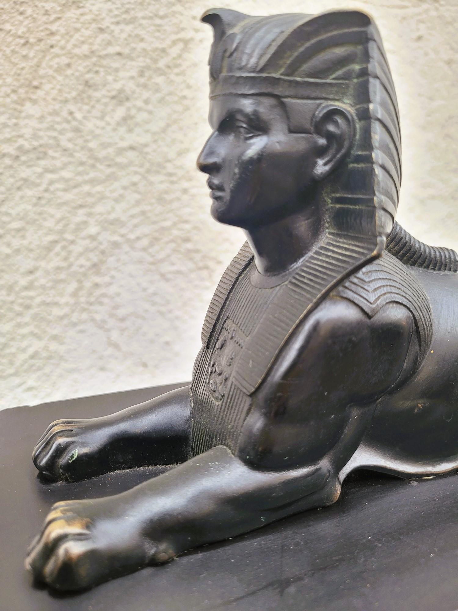 Large clock in the style of Egyptomania, in marble of different colors, decorated with stylized hieroglyphs, falcons and scarabs.

It is topped with a sphinx in patinated bronze.

Egyptomania is a very fashionable artistic movement in the 19th