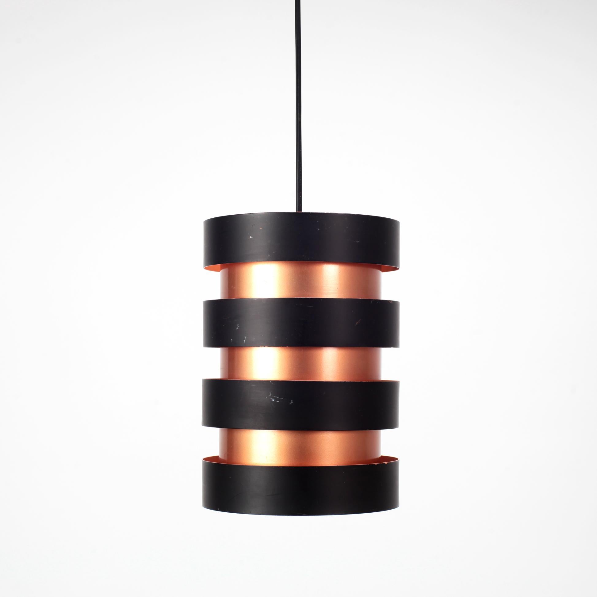 The iconic 'Eiffel' ceiling lamp designed by Jo Hammerborg for Fog & Morup. From Denmark in the 60s.

Beautiful design with the copper inner cylinder with 4 black outer rings. Orange interior screens, which provide very warm lighting.

1 E27
