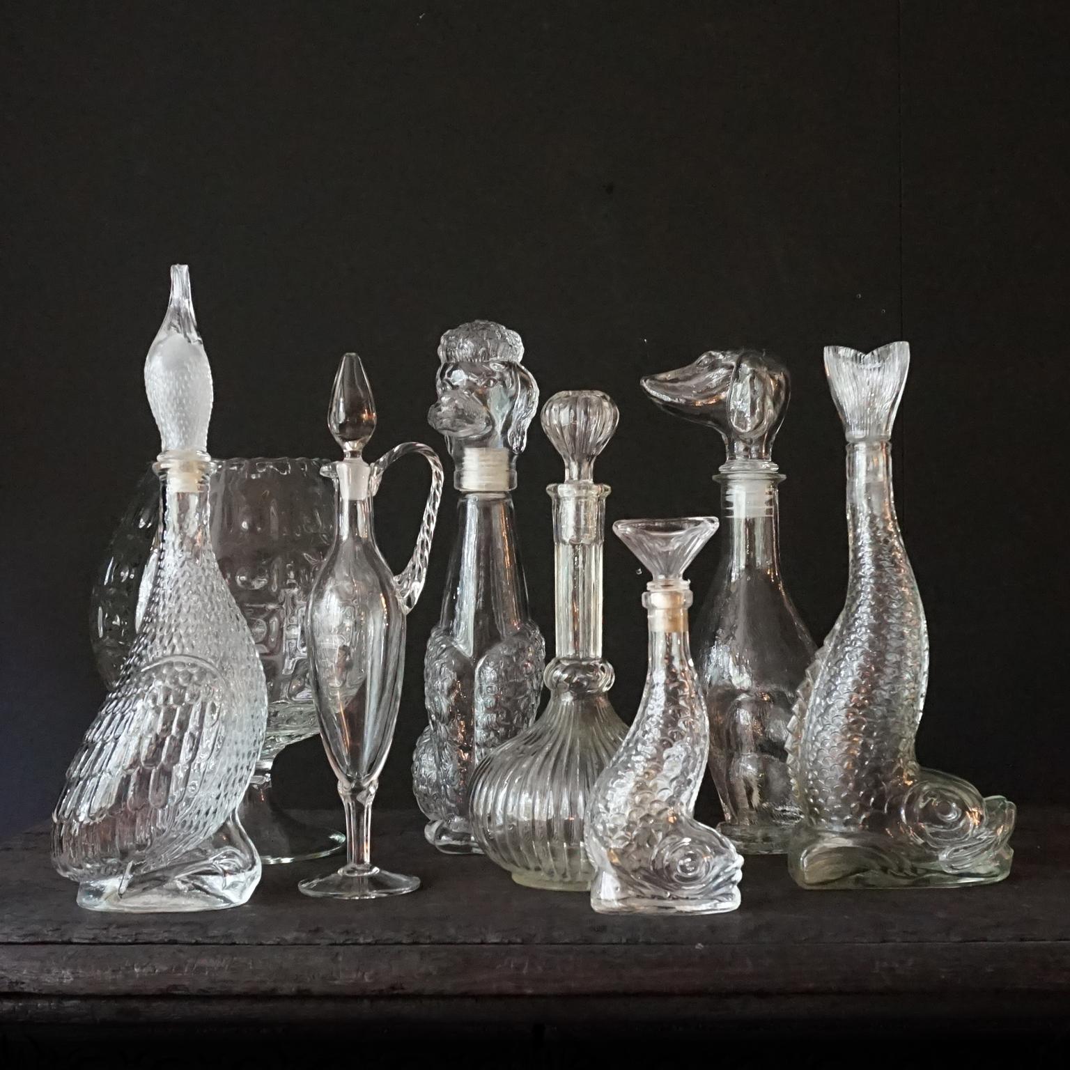 Very decorative rare clear glass set of eight different size Italian pressed glass bottles.
This set is almost completely animal themed, a duck, a poodle, a dachshund and two fishes. But also a pressed Brutalist large cognac glass a petite blown