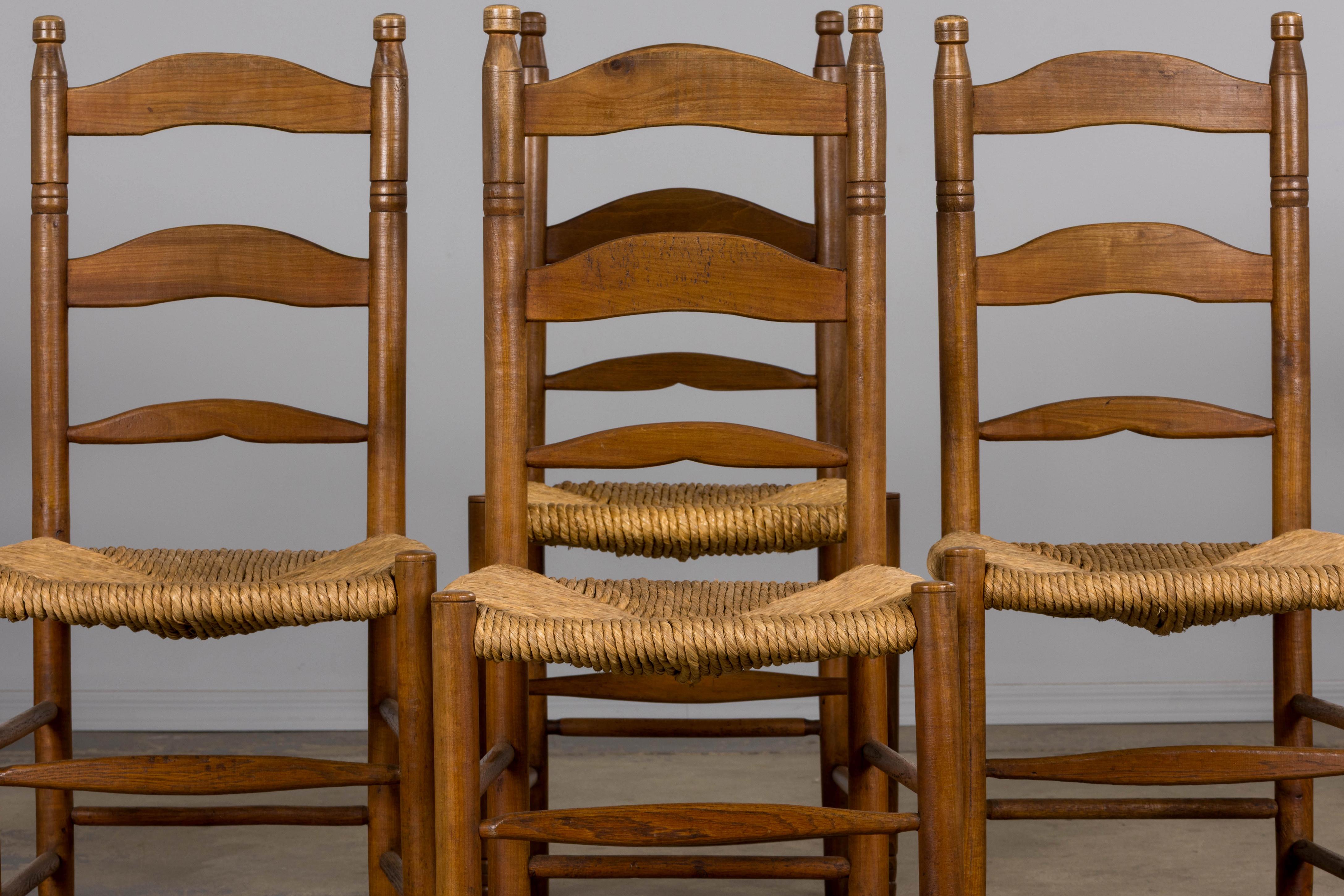 Un rústico conjunto de ocho sillas de granja con respaldo de escalera, de finales del siglo XIX, procedentes de la Provenza francesa. Talladas a mano en arce macizo, las sillas presentan elegantes armazones con respaldo de escalera y remates. Las