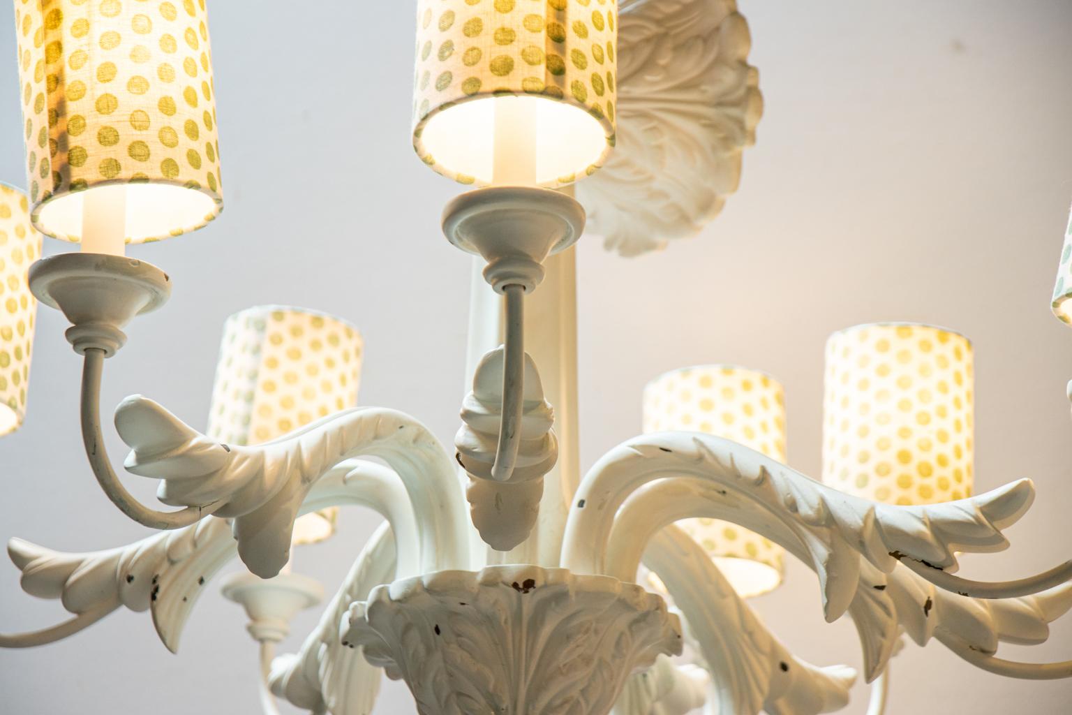 White painted eight arm chandelier with scrolled foliage accents on the arms and layered acanthus leaf dome shaped finial at the base of the column. Please note of wear consistent with age including paint, chips exposing the base material