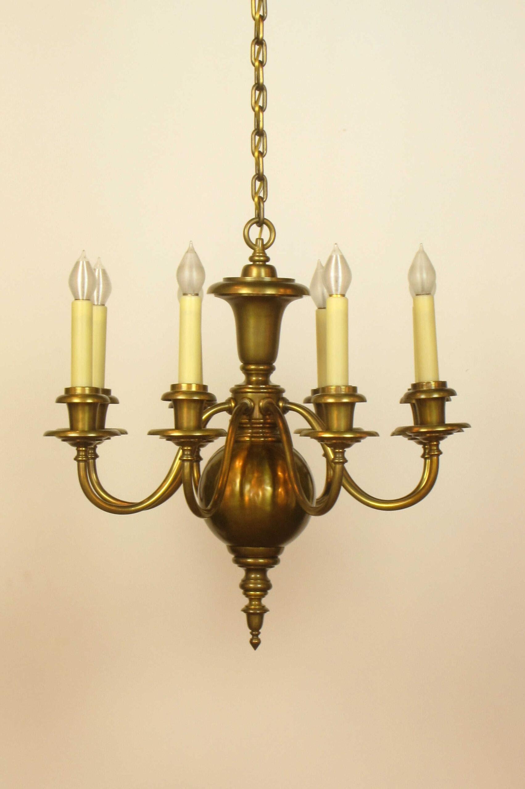 Eight Arm Colonial style Chandelier. Antique brass finish. C. 1910
A fine example of decorative lighting from the early electric period. Heavy brass chain and canopy. An urn form top, eight up curved arms, and a bottom ball. This piece has a very