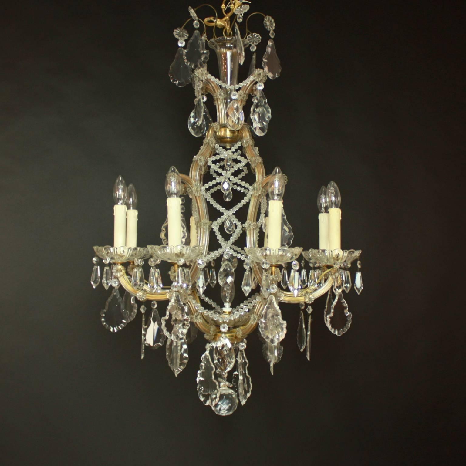 An eight-arm Marie The´re'se style crystal chandelier, Austria, circa 1910. The pear-shaped frame supports four arms that folk into two, holding altogether eight lights. The frame is adorned with layers of glass-stripes and rosettes, a trelliswork