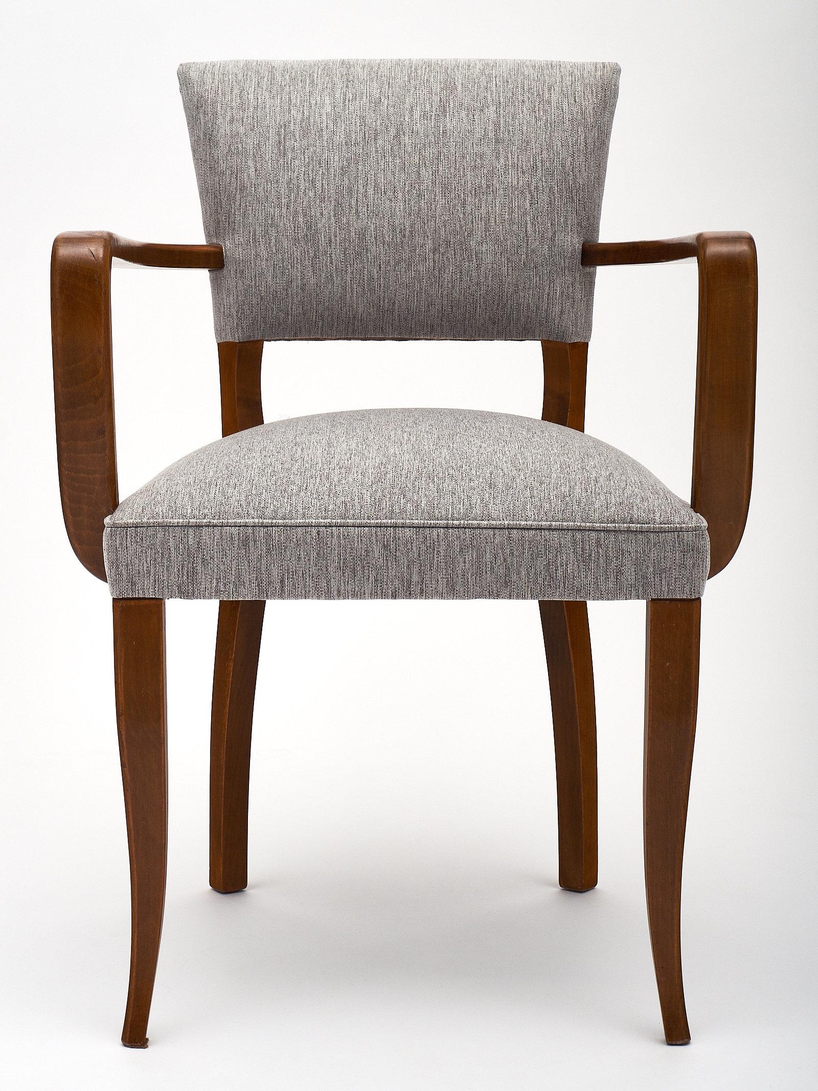 A set of eight French Art Deco bridge chairs made of walnut and newly upholstered in a grey linen blend. We love the attention to detail in the curved wood arms and saber legs. Elegant and versatile, these are indispensable features in your modern