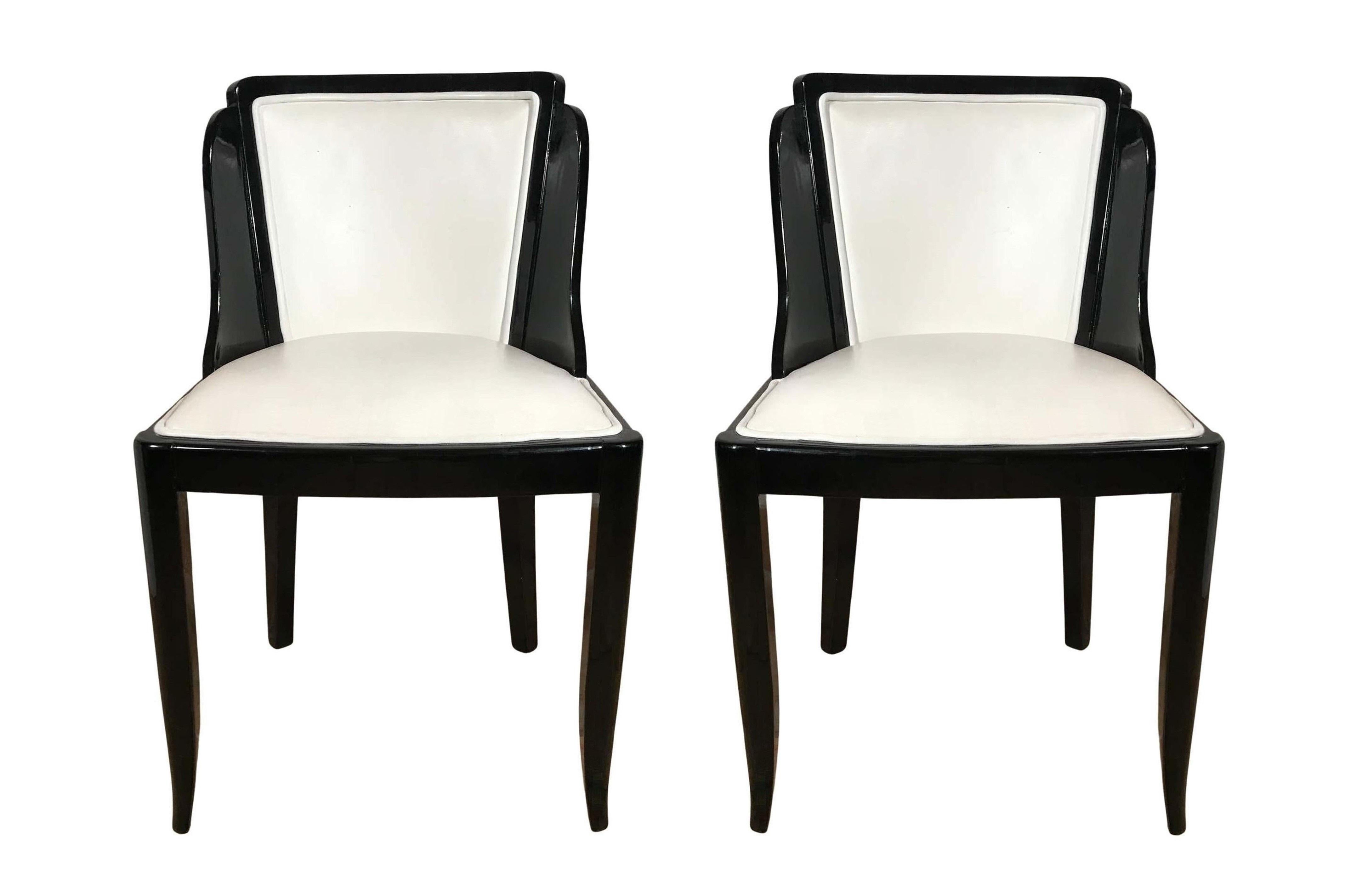 A truly stunning and rare set of tailored dining chairs were made in the 1930’s. Excellent joinery and craftsmanship, made from hardwood frames realized in lustrous black lacquer with premium genuine white leather seating surfaces. Legs are saber