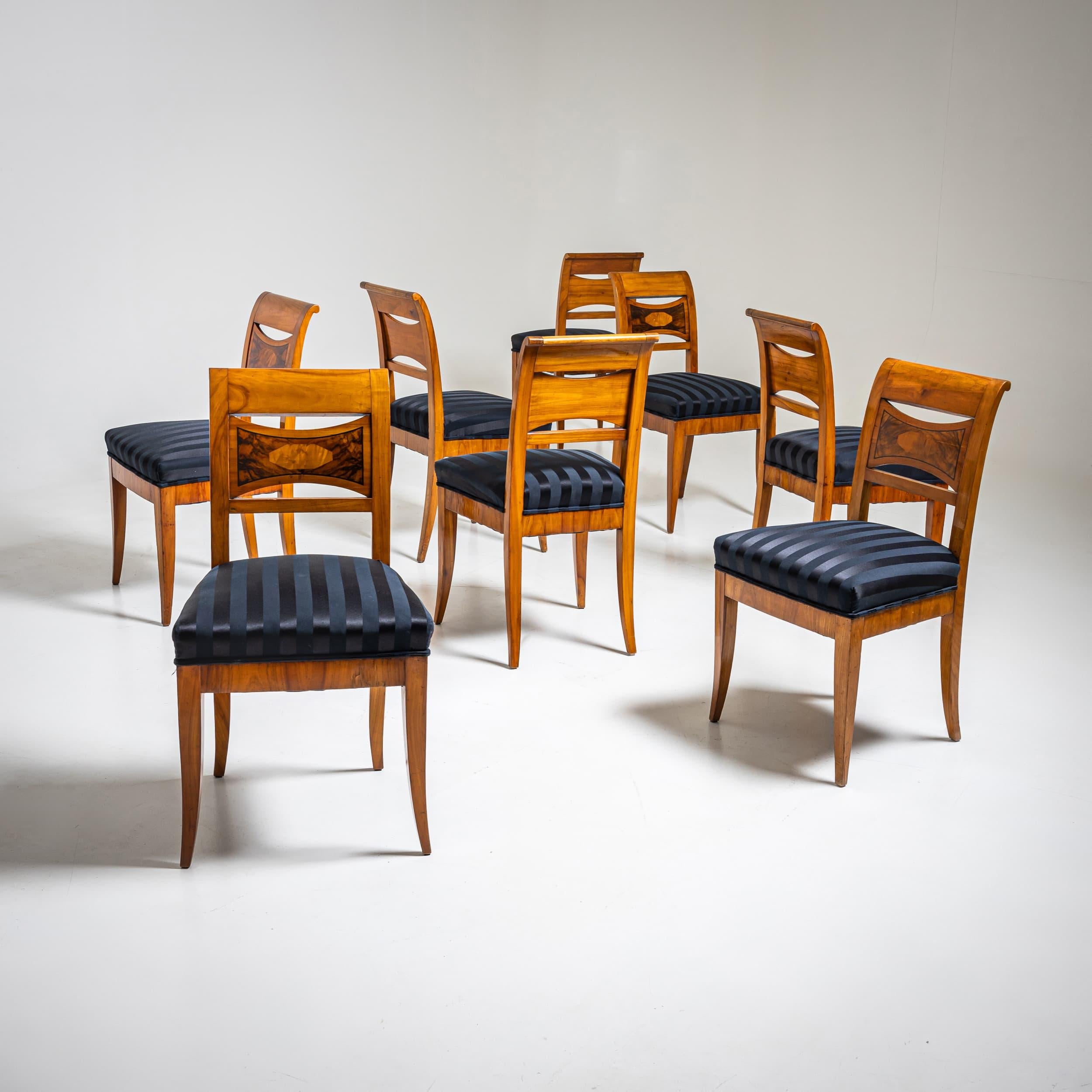 Set of eight Biedermeier chairs made of cherry wood with burl inlays on the slightly curved backrests. The seats are upholstered in black striped fabric.
