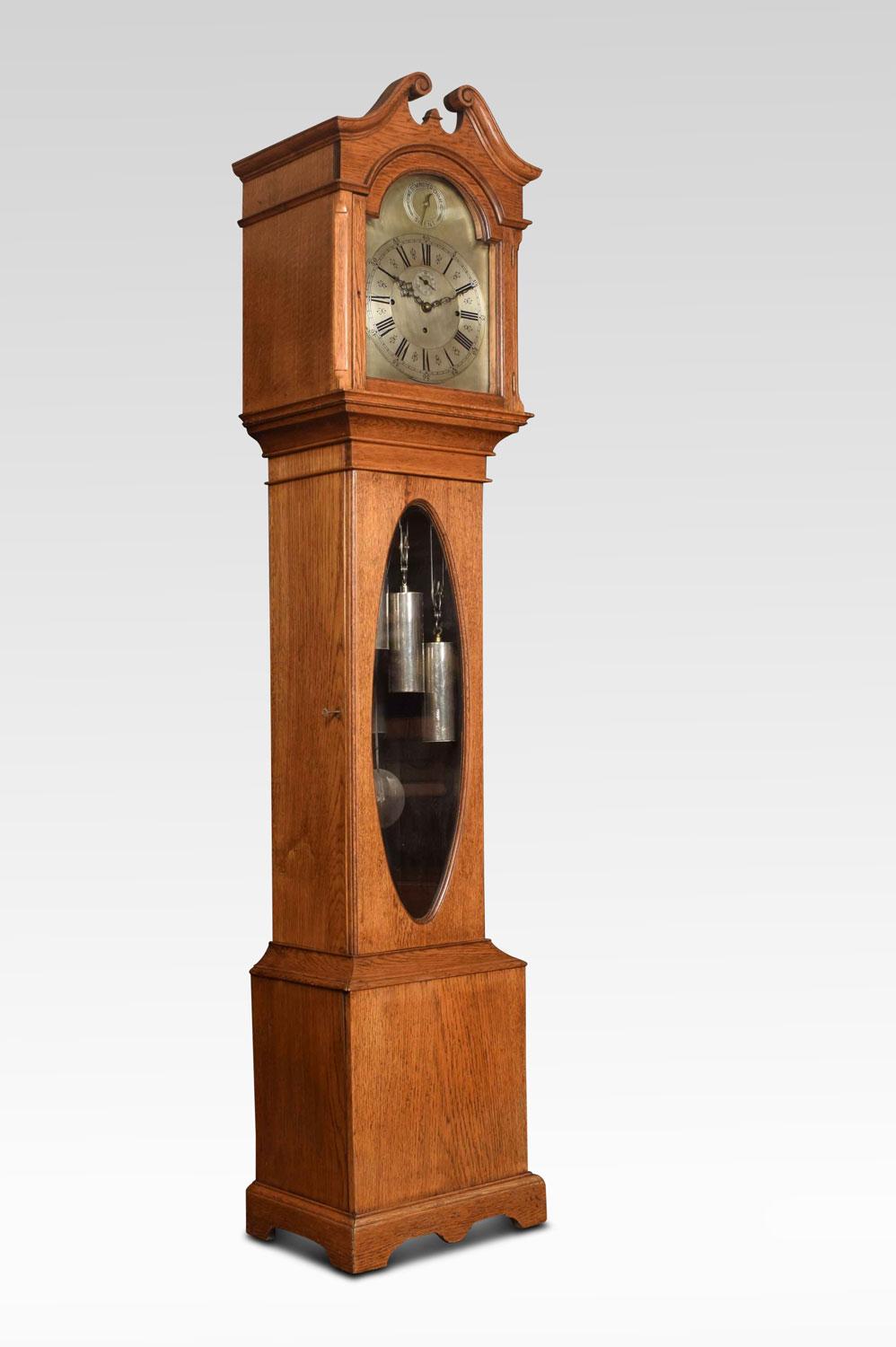 Oak musical and quarter chiming long case clock, having arched silvered dial with Roman numerals, and auxiliary dial having option of Westminster Chimes / Silent. The movement with anchor escapement, striking mechanism with five chiming tubes and