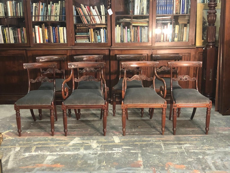 Elegant set of English Regency mahogany dining chairs consisting of two arm chairs and six side chairs. These magnificent Regency Chairs have a superb carved concave top rail and carved center rail with inset rosettes. The chairs have a high style