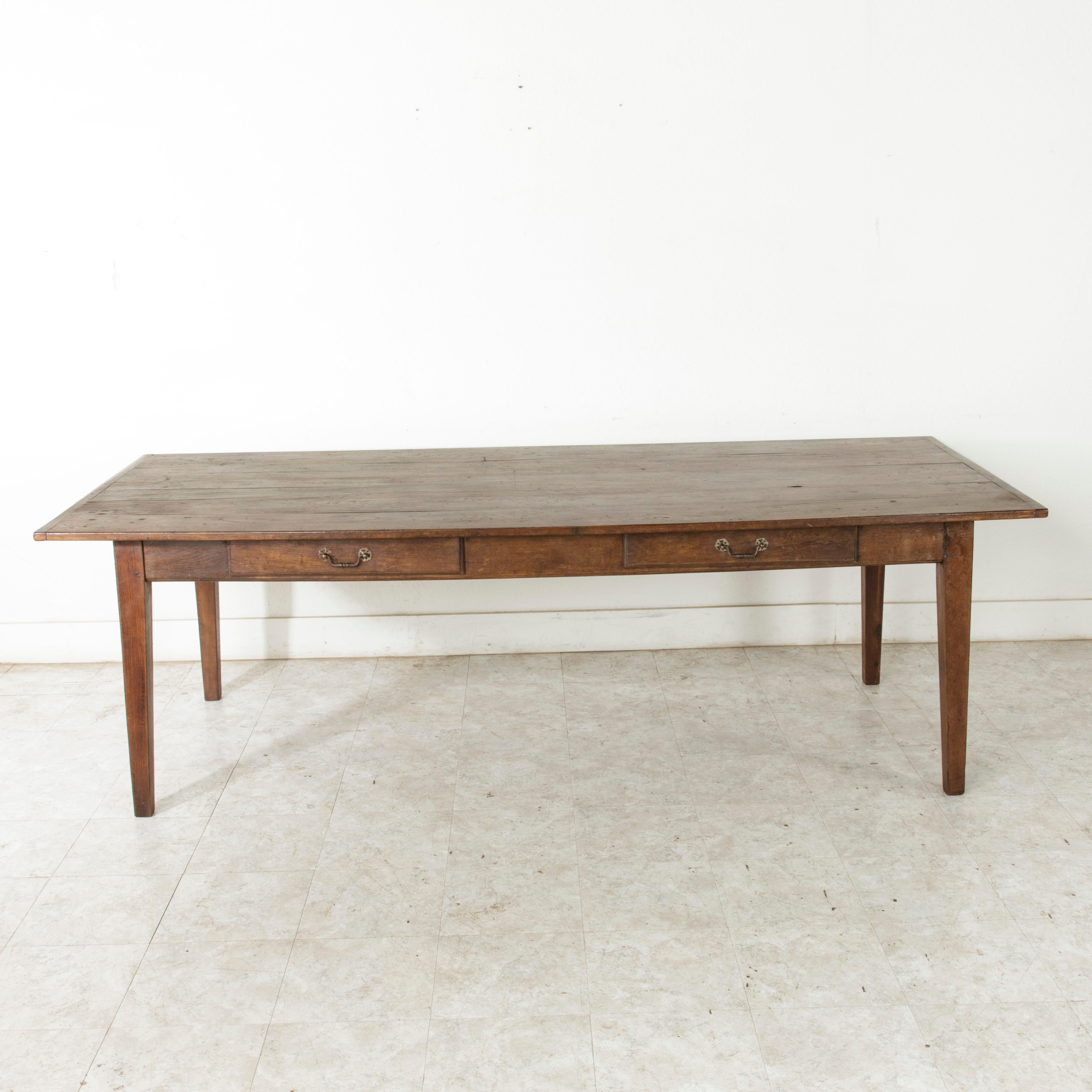 This turn of the 20th century artisan-made farm table is from the region of Le Perche, a sub-region of Normandy, France. Its hand pegged oak top measures 94.5 inches long and 39.25 inches wide. Resting on a hand pegged oak base with four gently