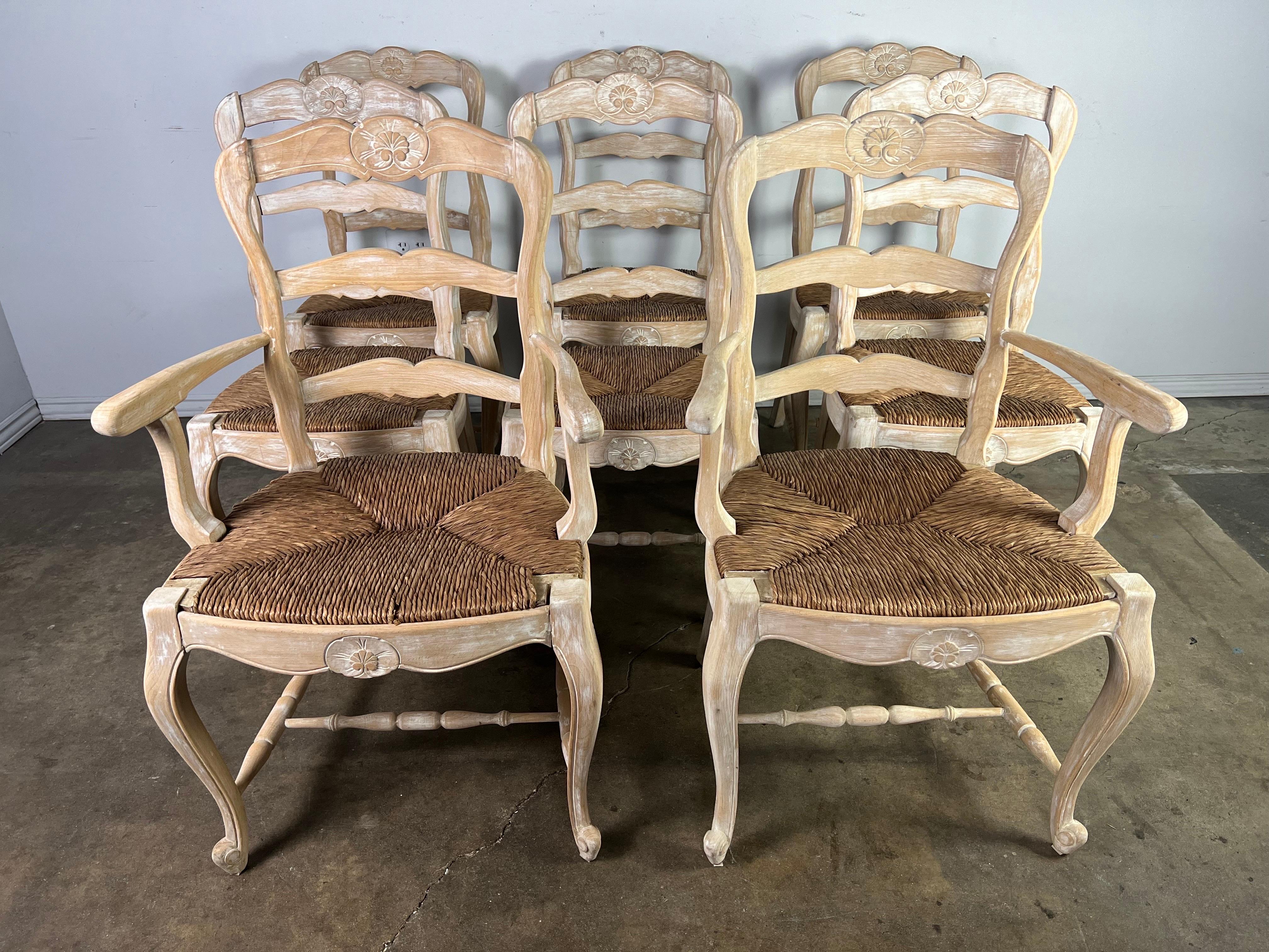 Set of eight French dining chairs w/ rush seats. The ladder back chairs stand on four cabriole legs that end in a rams head foot. The chairs have been stripped to their natural walnut finish. Original rush seats still in great condition.