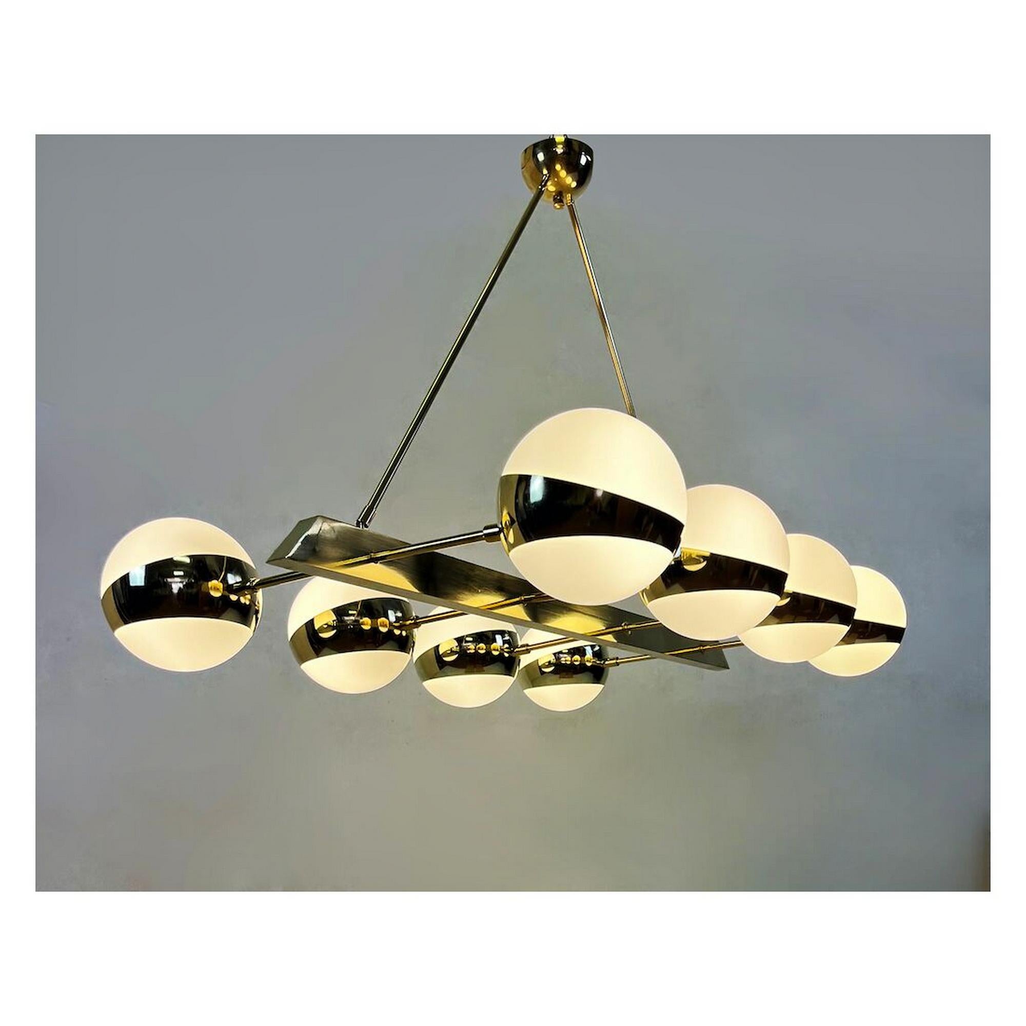 Ce luxueux lustre horizontal de style vintage apporte une clarté sculpturale et une chaleur ambiante aux salles à manger, aux salons ou aux espaces commerciaux aménagés. Un élégant cadre rectangulaire en laiton, suspendu par deux tiges coudées,