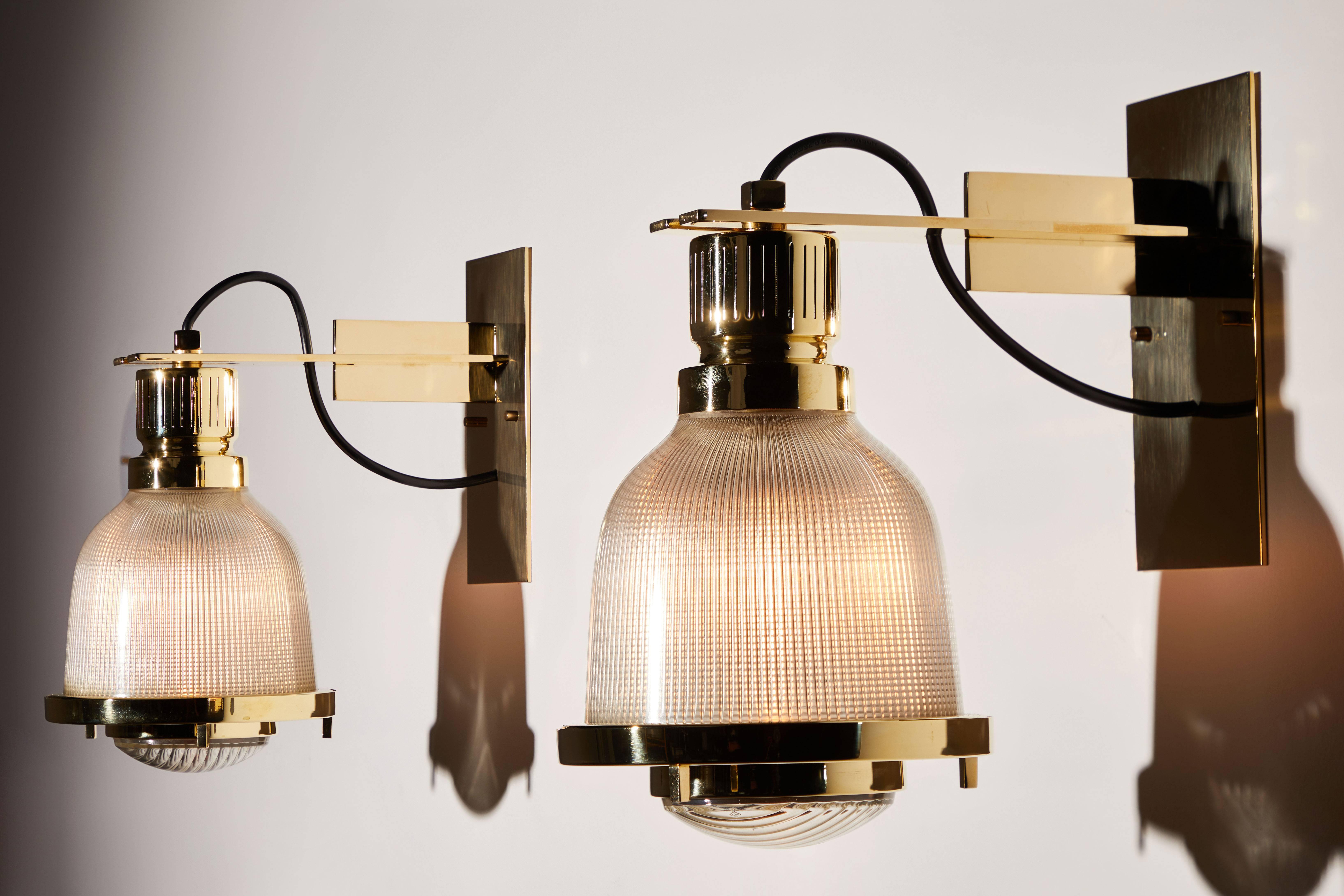 Four sconces designed by Guiseppi Ostuni and manufactured in Italy, by Oluce circa 1960s. Fully restored brass and holophane glass. Rewired for US junction boxes. Each light takes one E14 60 watt maximum European candelabra bulbs. Please read