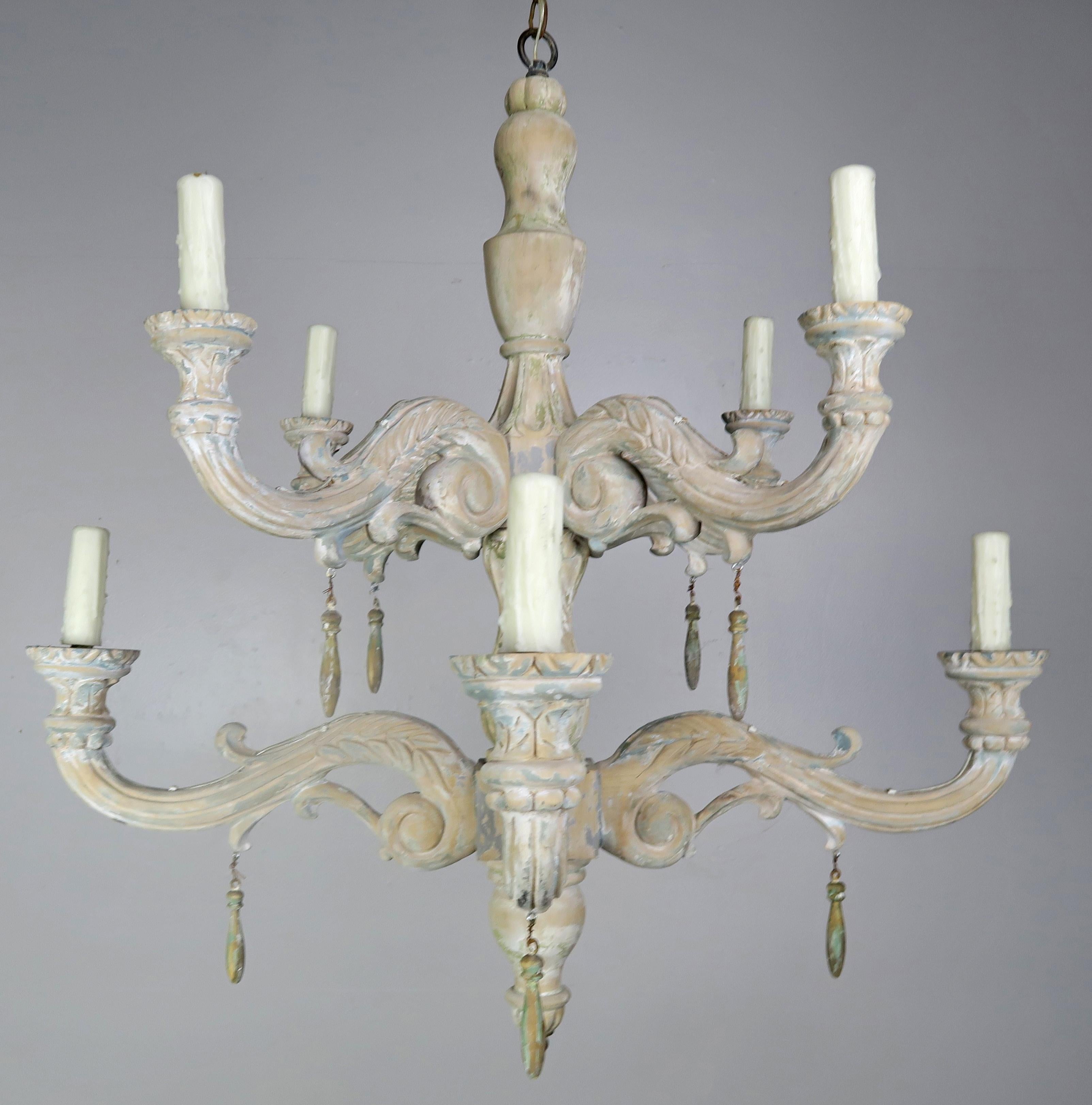 Eight-light Italian style carved wood two-tier chandelier with remnants of paint throughout. This fixture has a beautiful worn painted finish. The fixture is newly rewired with drip wax candle covers. Includes chain and canopy. A pair is available