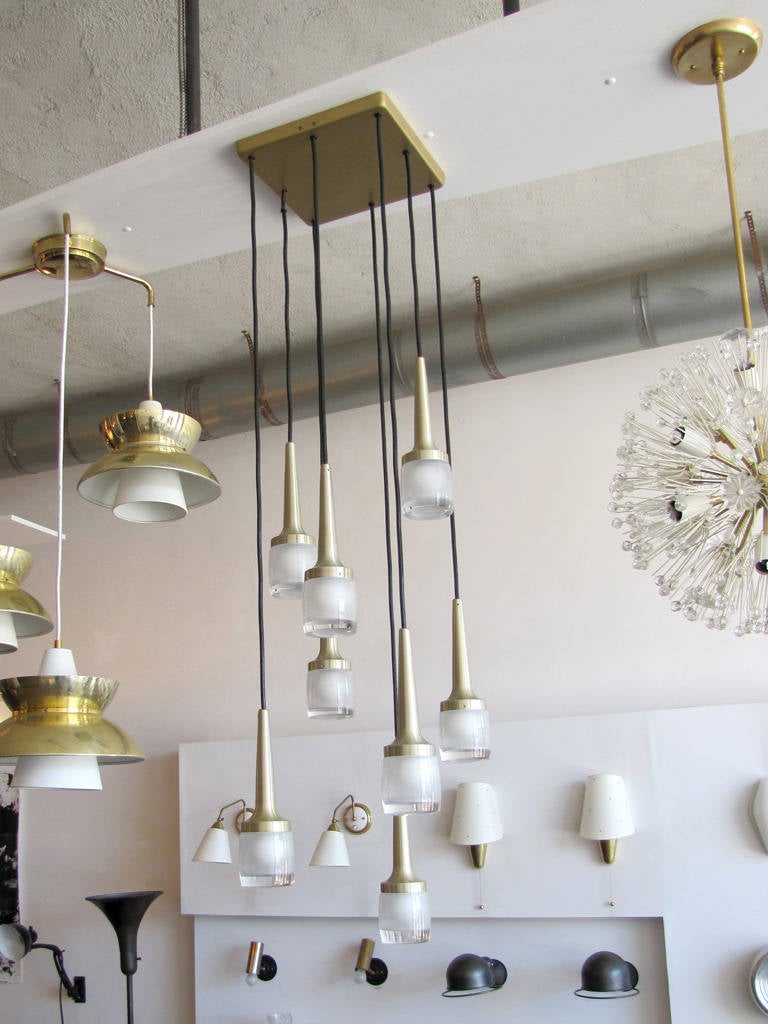 Stunning eight hanging lights by Staff of Germany, encased in heavy molded glass, brushed brass, lengths and configuration adjustable, currently in square brass canopy, can be hung individually.