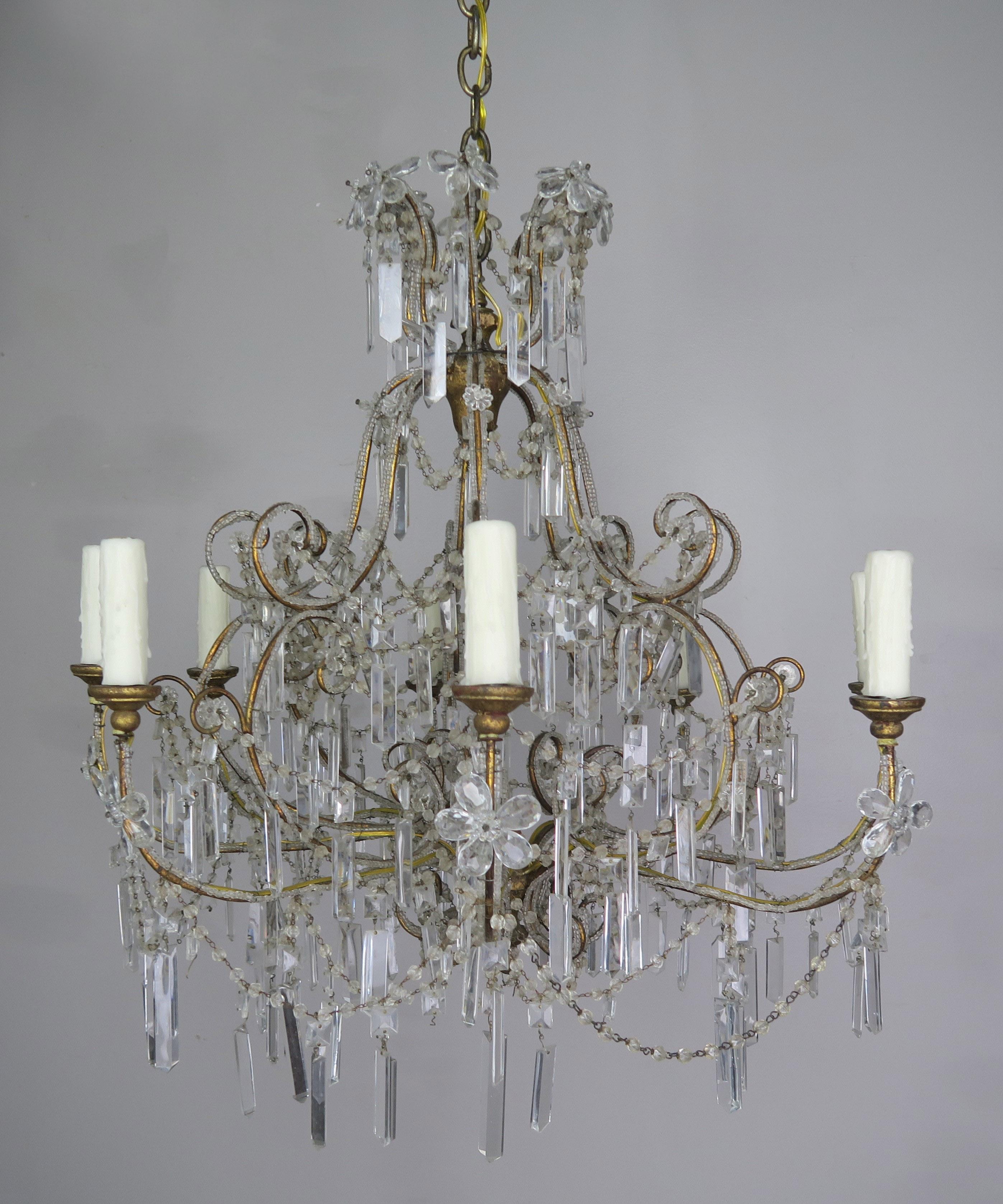 Eight light crystal beaded chandelier with handmade crystal flowers throughout. The fixture is adorned with garlands of English cut beads and sphere shaped crystals throughout. The fixture is newly rewired with cream colored drip wax candle covers.