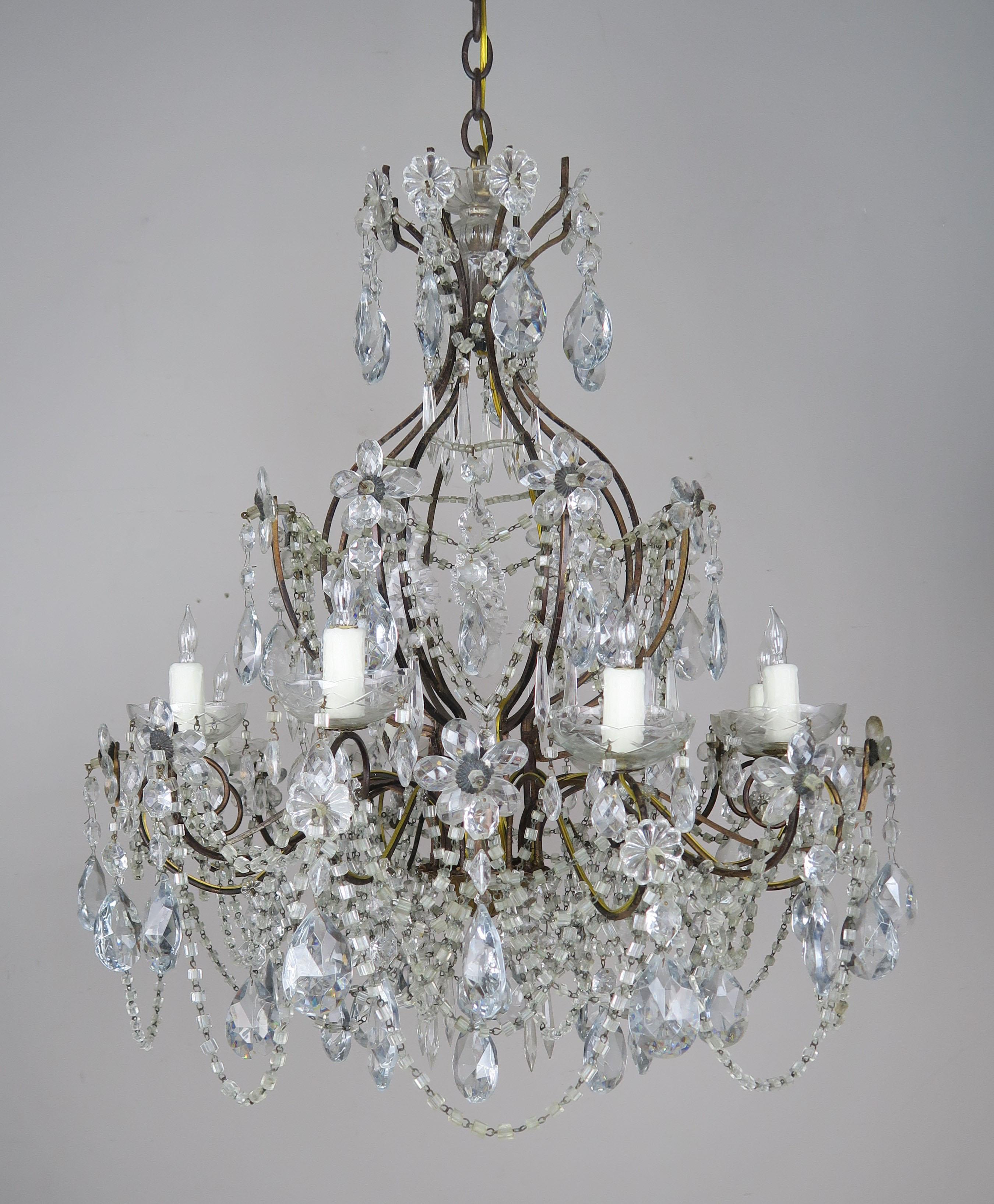 Eight-light French gilt metal crystal macaroni beaded chandelier adorned with crystal including crystal flowers throughout. The chandelier has been newly rewired with cream colored drip wax candle covers.