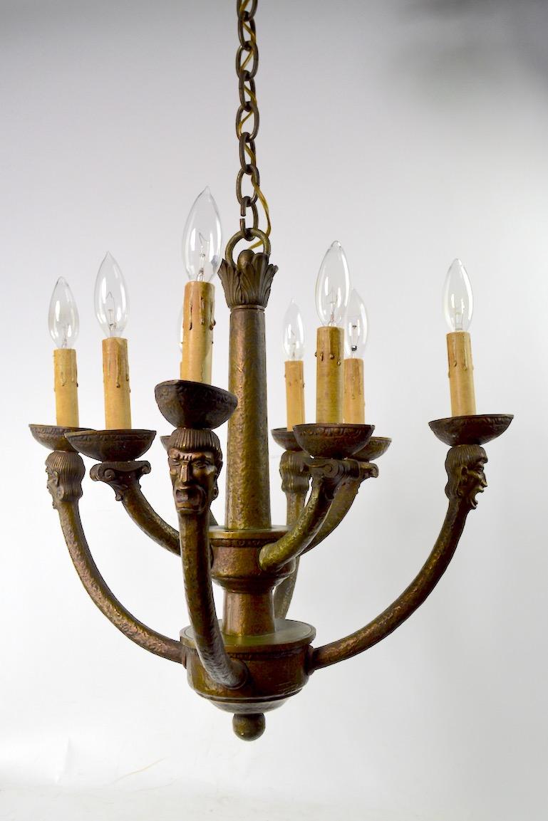 Wonderful cast bronze eight-light Gothic Mission chandelier having male heads on the outer arms, and column capitals on the inner arms. The fixture is in great original condition, working and ready to install. Height without chain 18 inches.