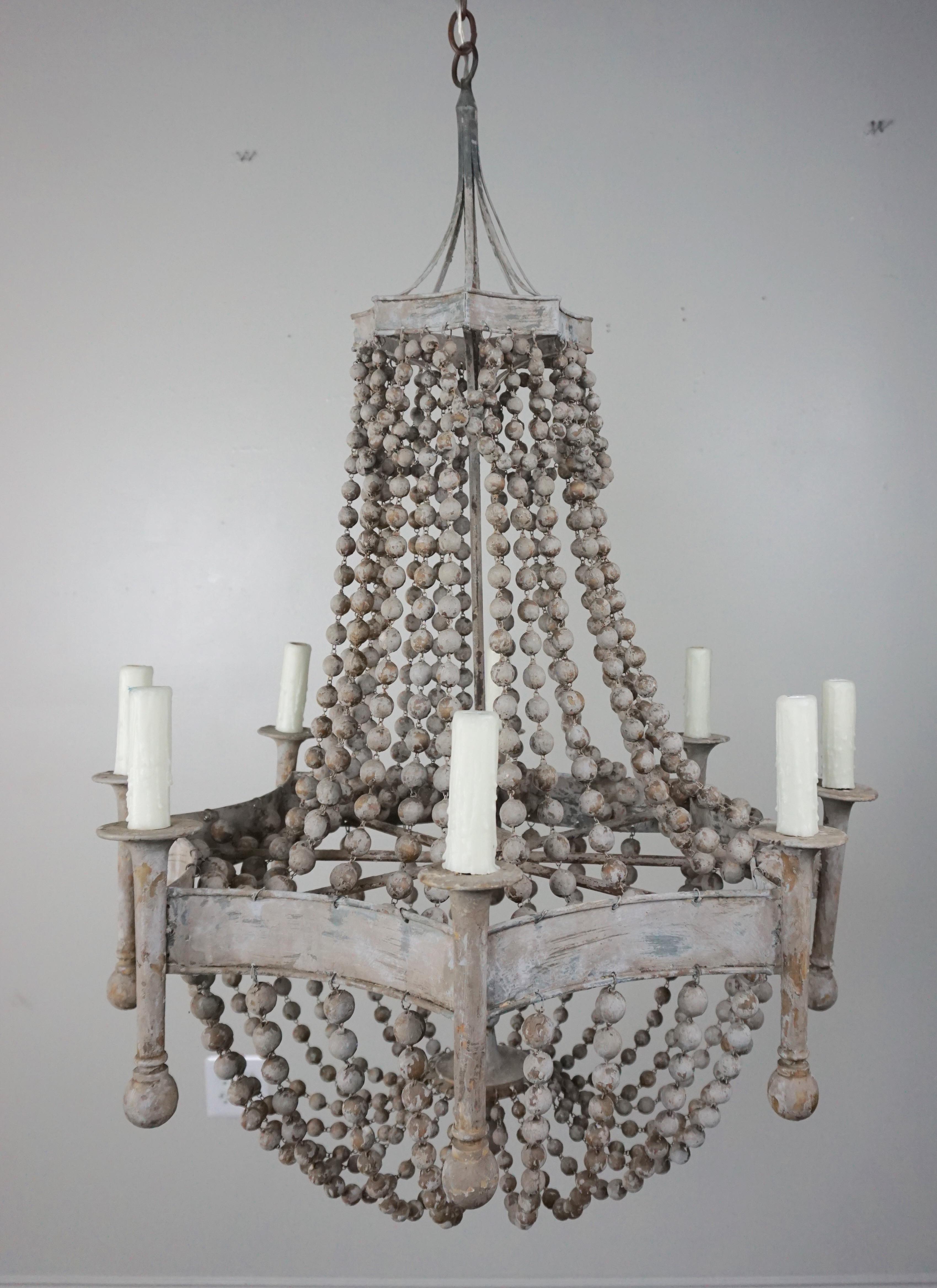 Eight light soft gray painted wood beaded and metal chandelier. The fixture is newly rewired with drip wax cream colored candle covers. Garlands of wooden beads drop down to create a beautiful basket shape. Chandelier includes chain and canopy and