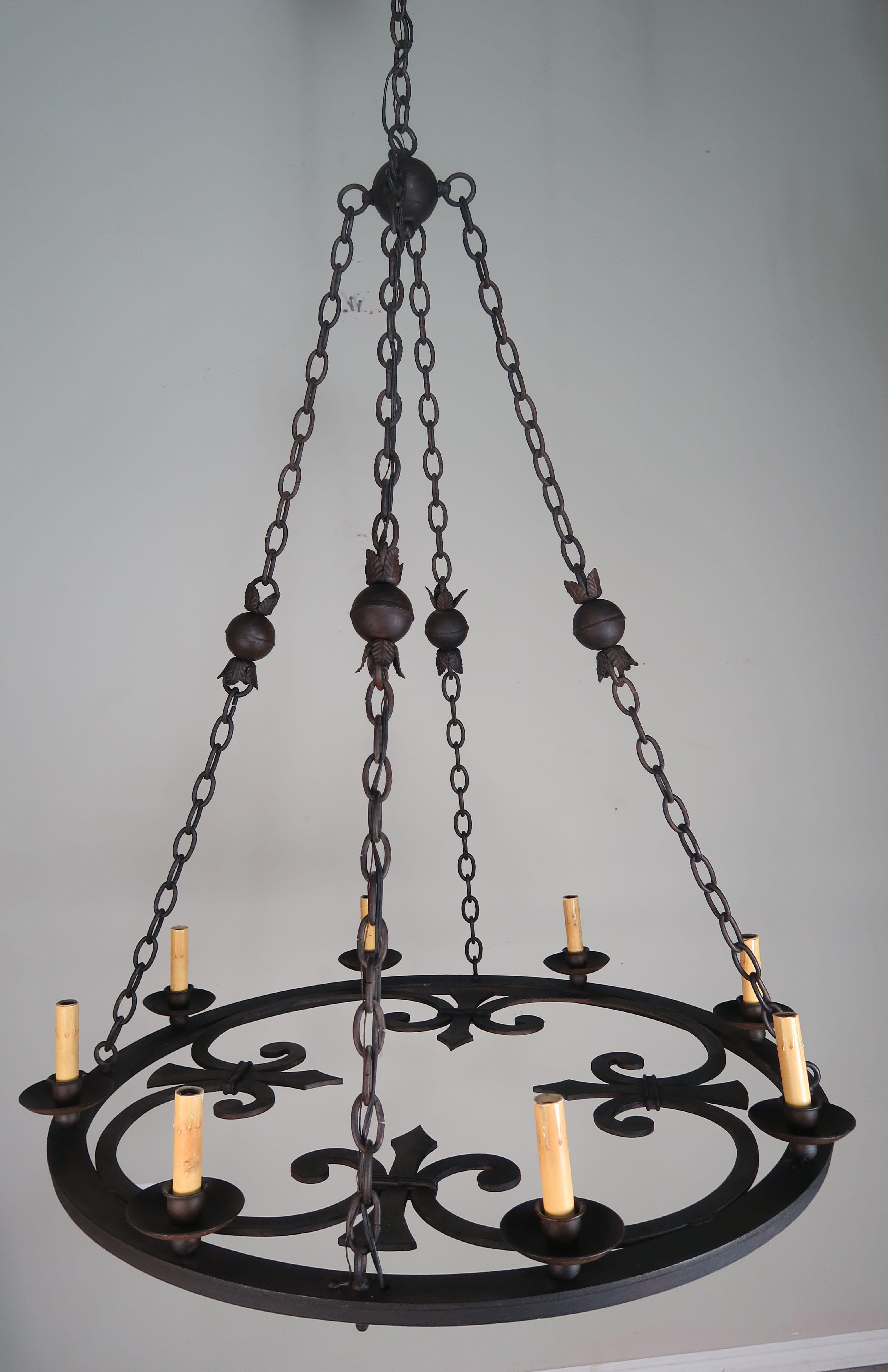 Eight-light Spanish wrought Iron circular shaped chandelier with four fleur de lys. The chandelier is attached to three chains that meet at a center iron ball and then extends up to the canopy. More chain available if needed. The fixture has been