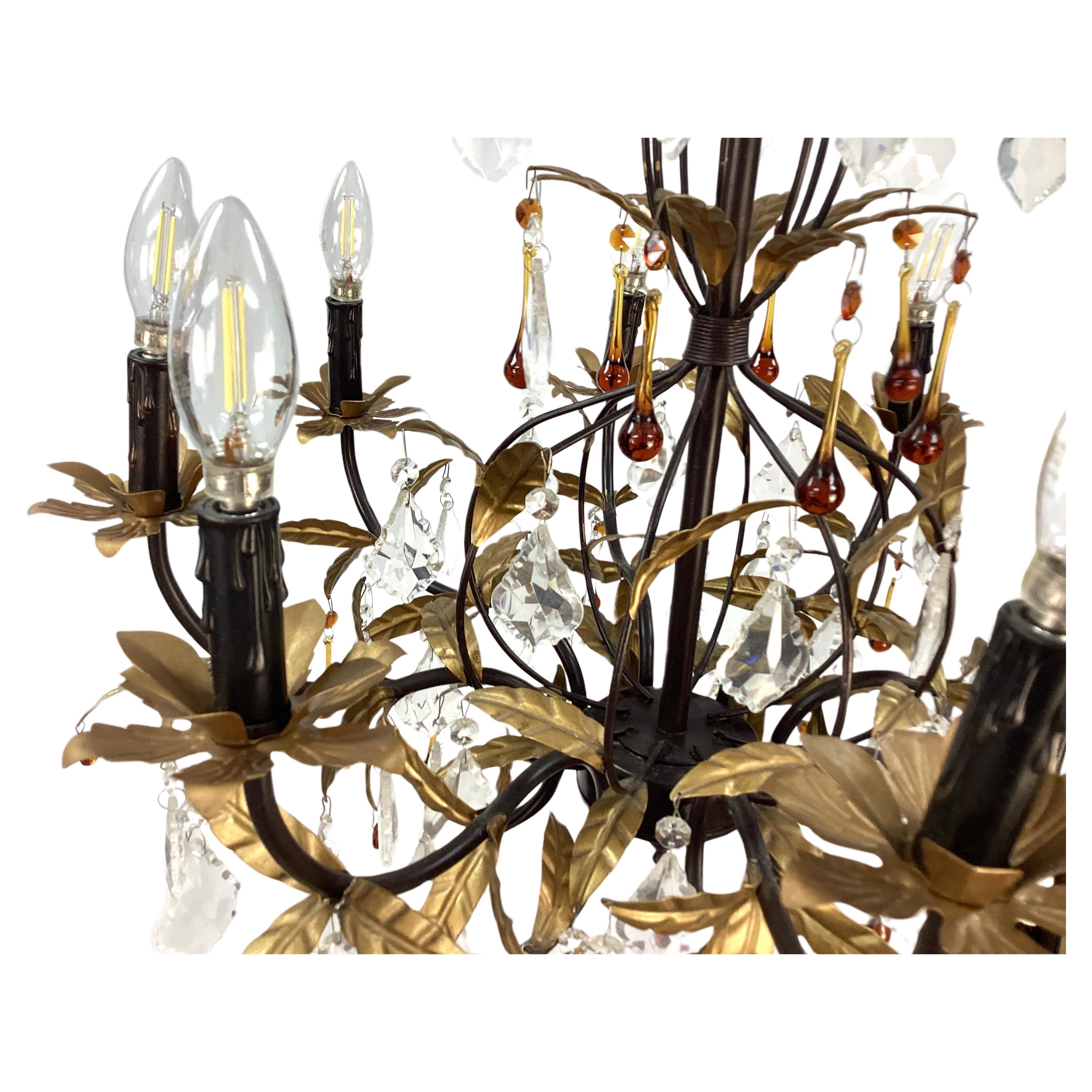 Eight Light tole Chandelier with gold gilt tole leaves. Finish. Features clear and amber crystal droplets and gold leaf accents. Uses 60 watt maximum chandelier bulbs. Includes 6ft. of chain. 